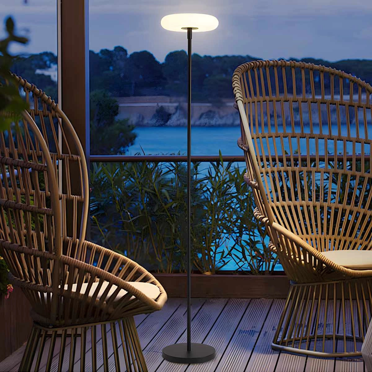 Modern black minimalist LED torchiere floor lamp with slim design and energy-efficient lighting standing in a room with a chair and wooden furniture.