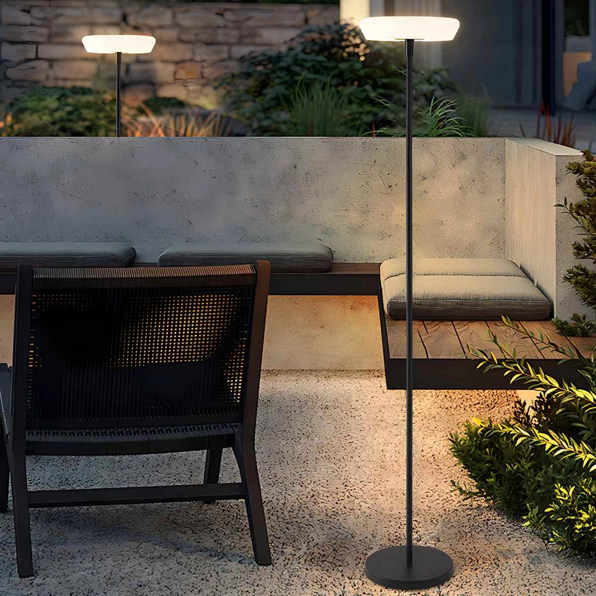 A modern black minimalist LED torchiere floor lamp with a slim design, placed in a contemporary living space next to a plant and furniture.