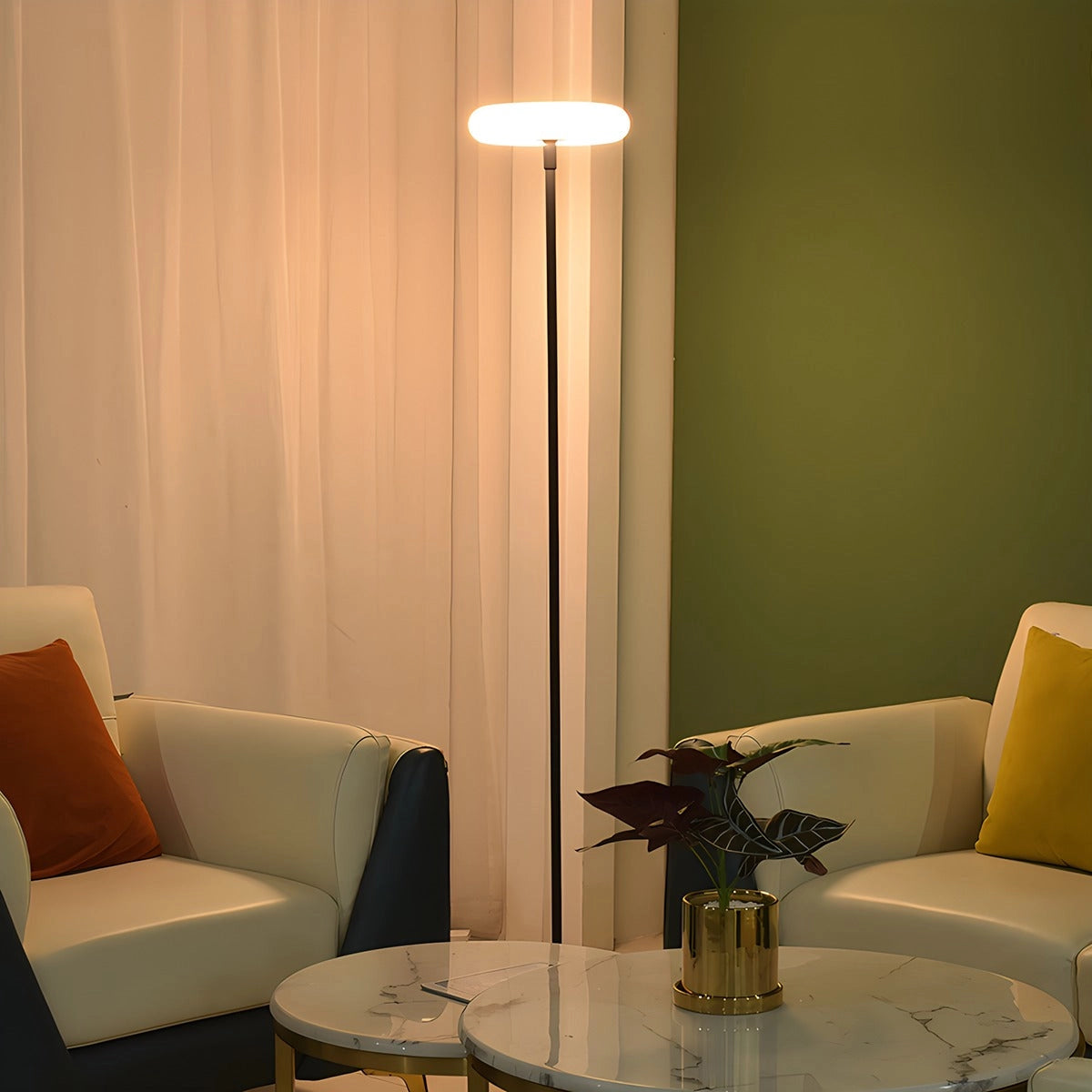 A modern black minimalist LED torchiere floor lamp stands beside a comfortable gray couch with cushions, illuminating the room with sleek and energy-efficient design. A small potted plant and a table are also visible in the background.