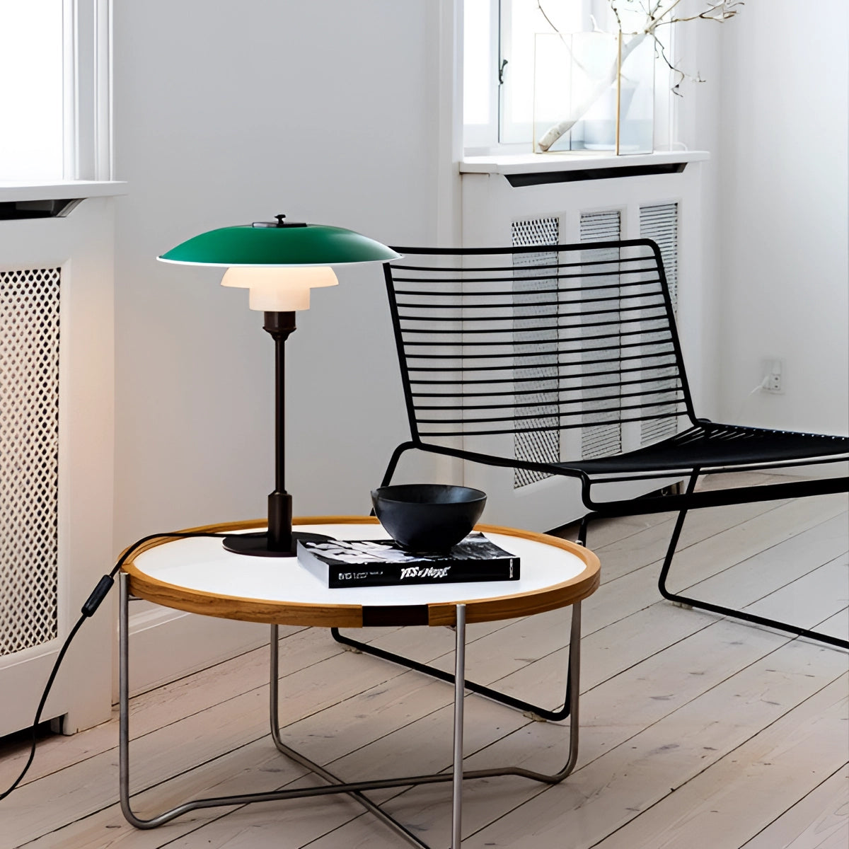 Modern black mushroom shade table lamp with adjustable neck and frosted glass, placed on a wooden surface in a stylishly designed interior.