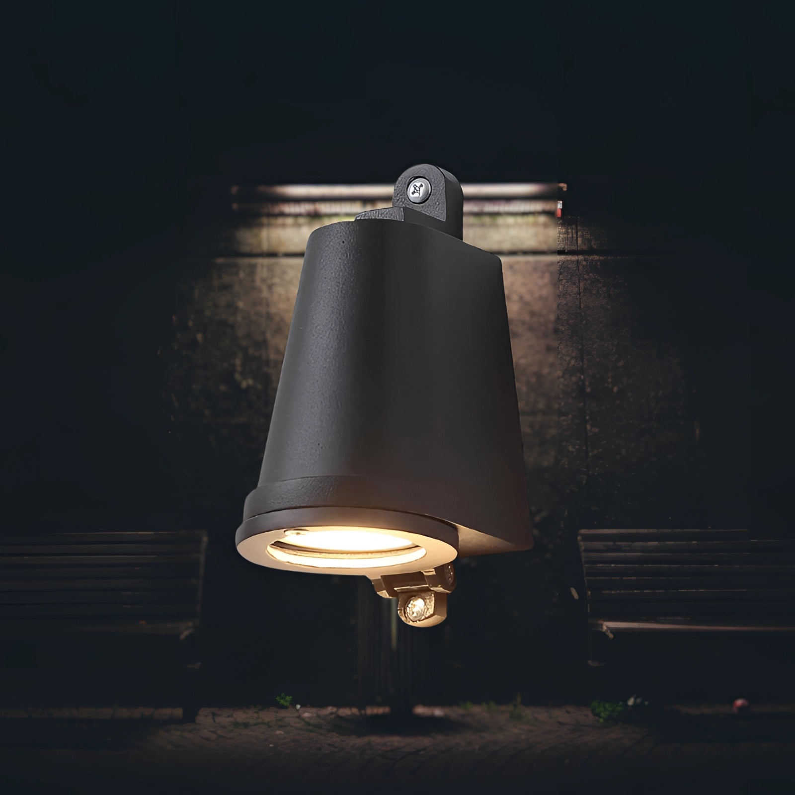 Modern black outdoor wall light mounted on a wooden exterior. The weather-resistant LED fixture emits a cool white light, designed for outdoor use. The sleek design complements various architectural styles, providing efficient illumination ideal for entryways, patios, or gardens.