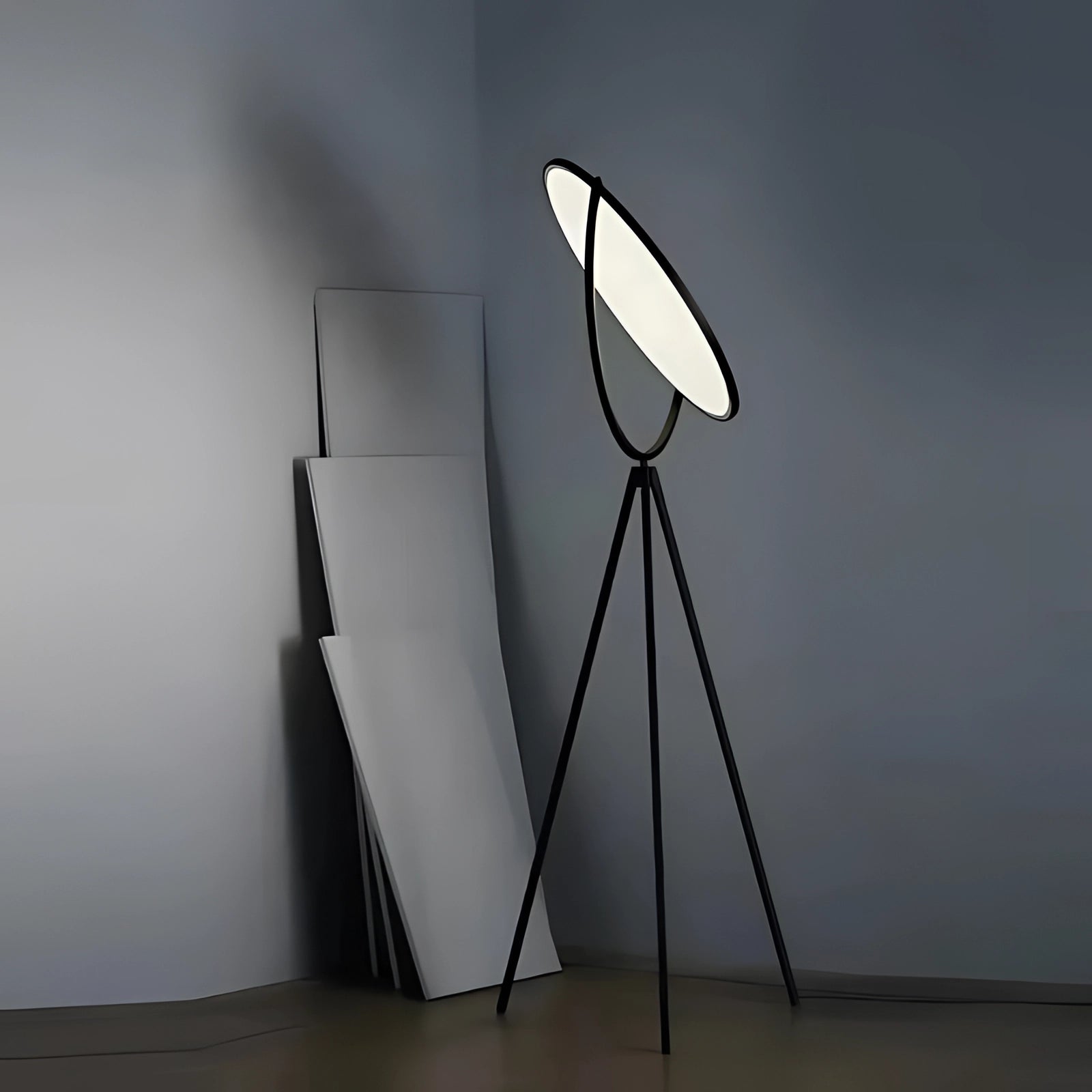 Modern black tripod floor lamp with adjustable height, featuring a minimalist design with wooden elements and a grey lampshade.