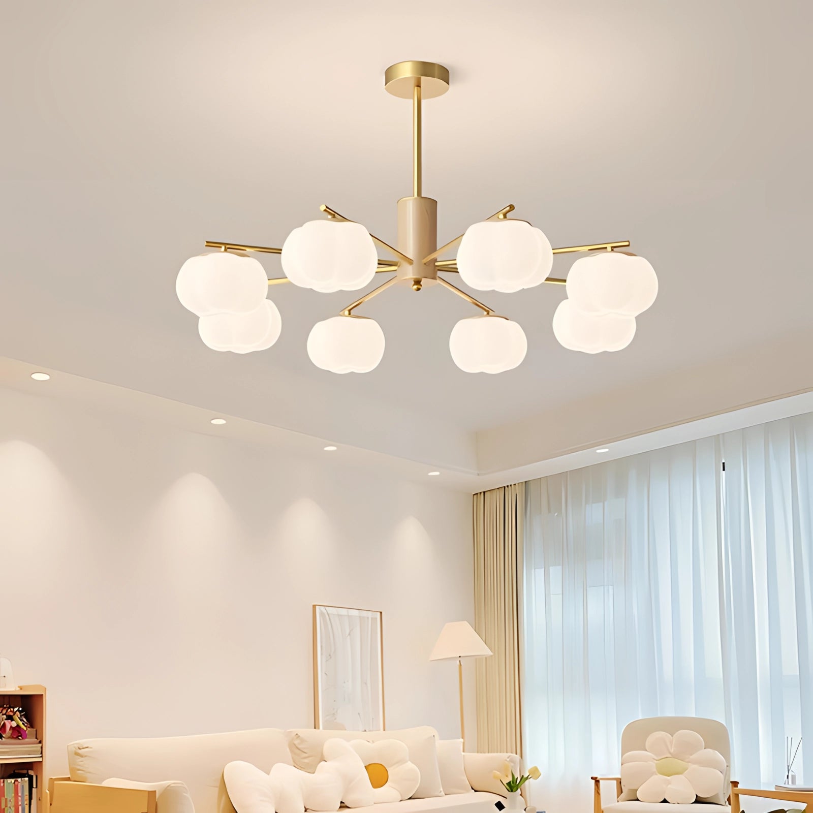 Modern brass chandelier with six milk glass lights hanging in a stylishly decorated room, featuring a window, a couch, and a table, complemented by white and yellow tones.
