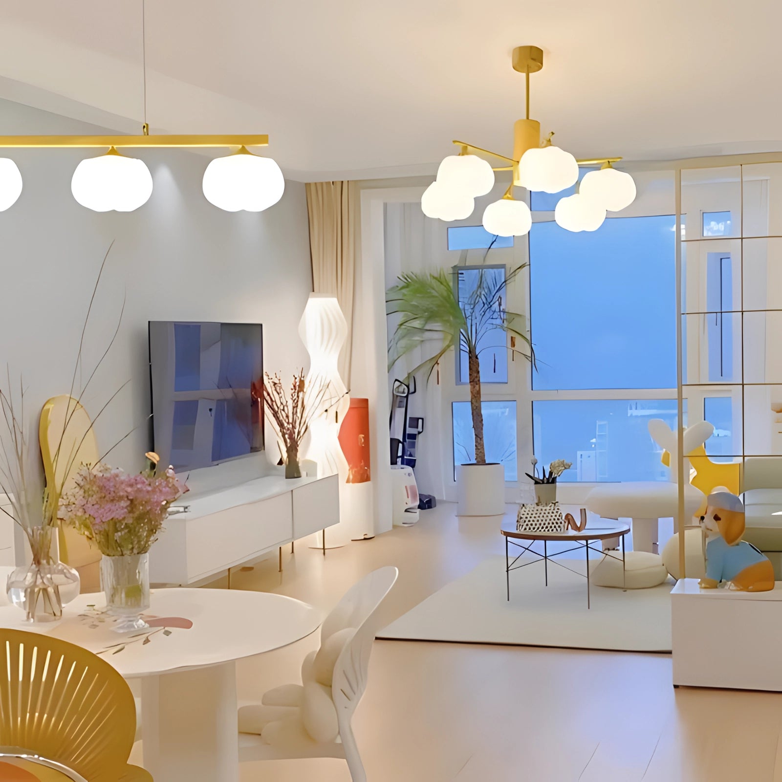 Modern brass 6-bulb chandelier with milk glass lights installed above a contemporary living room setting featuring a table, houseplants, and stylish furniture.