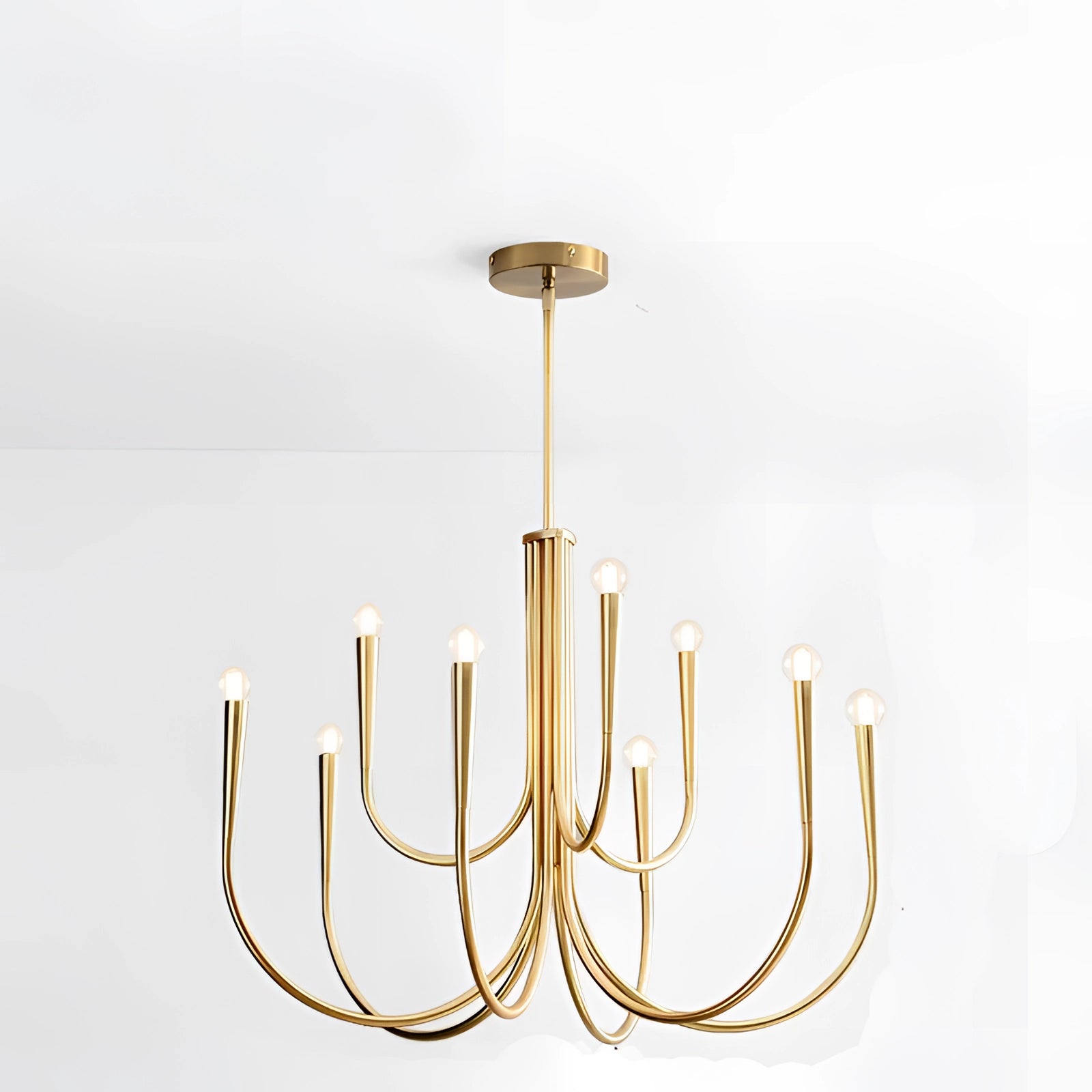 Modern brass chandelier with neutral light hanging above an oak dining table in a blue dining room, featuring artful design elements and natural materials like twigs and plants.
