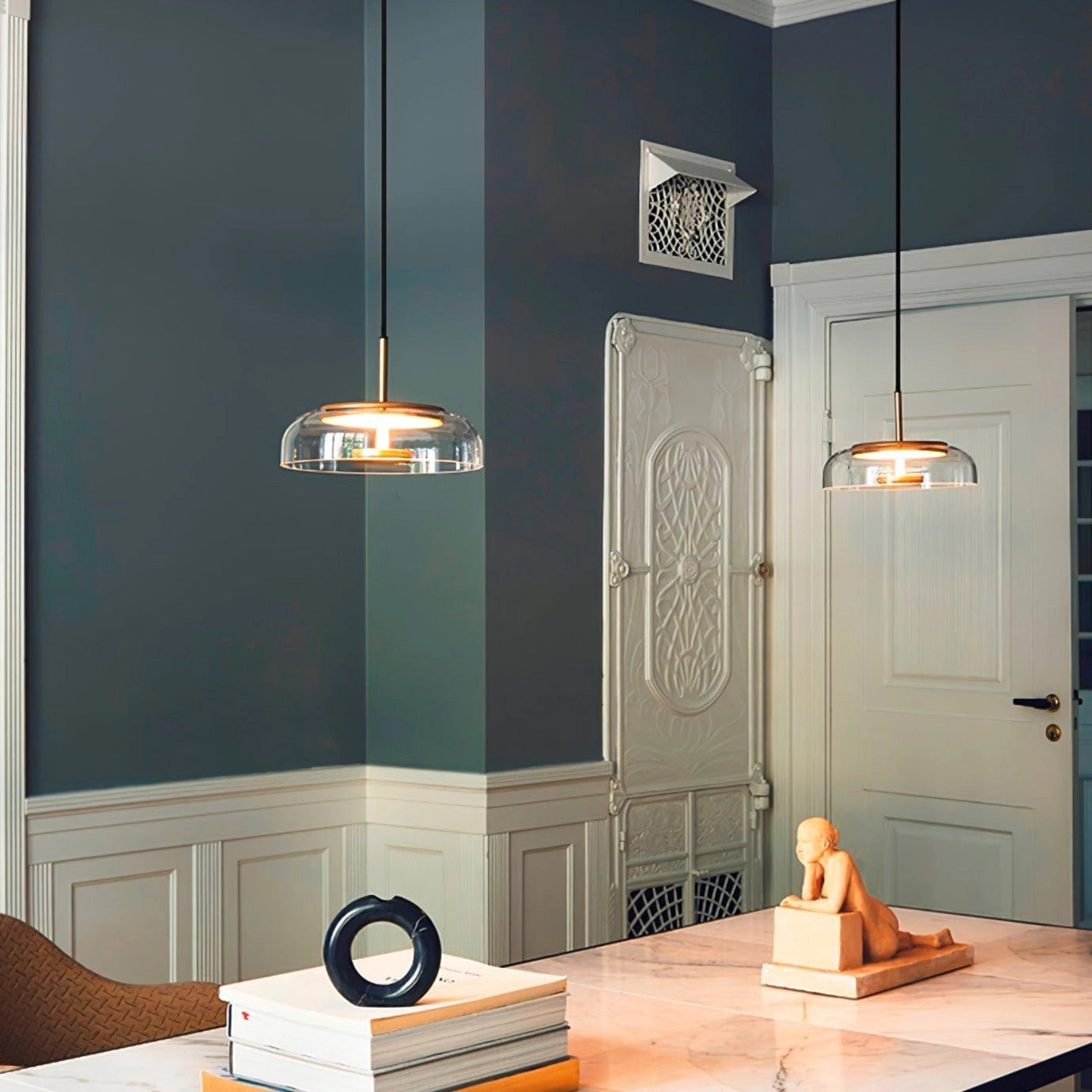 Modern brass and chrome LED pendant lights illuminating a minimalist interior with wooden flooring and a stylish table.