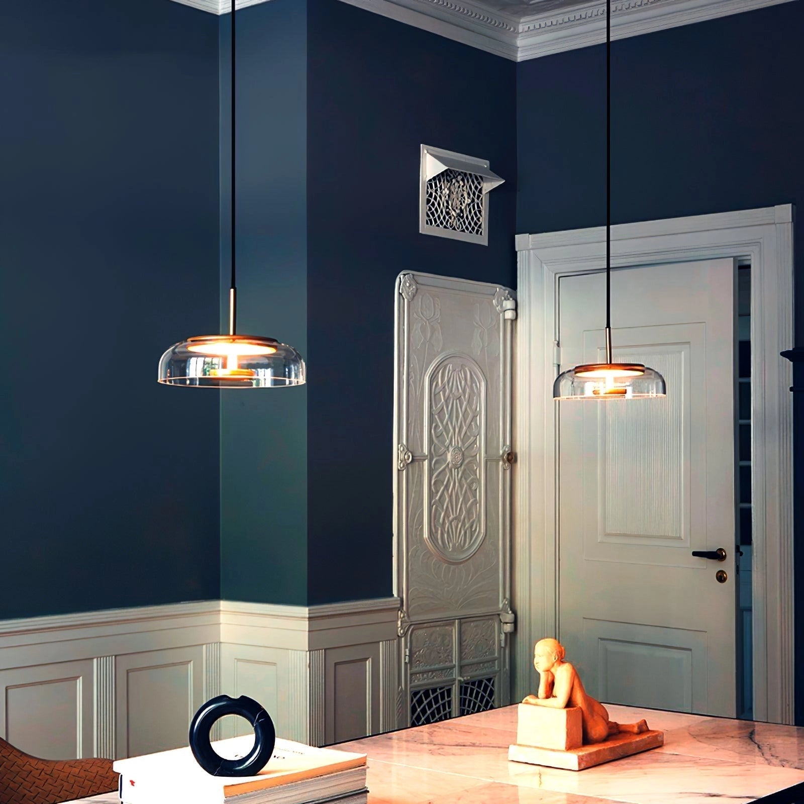 Modern brass and chrome LED pendant lights with a luxury minimalist design hanging above a wooden table in a stylishly designed interior space.