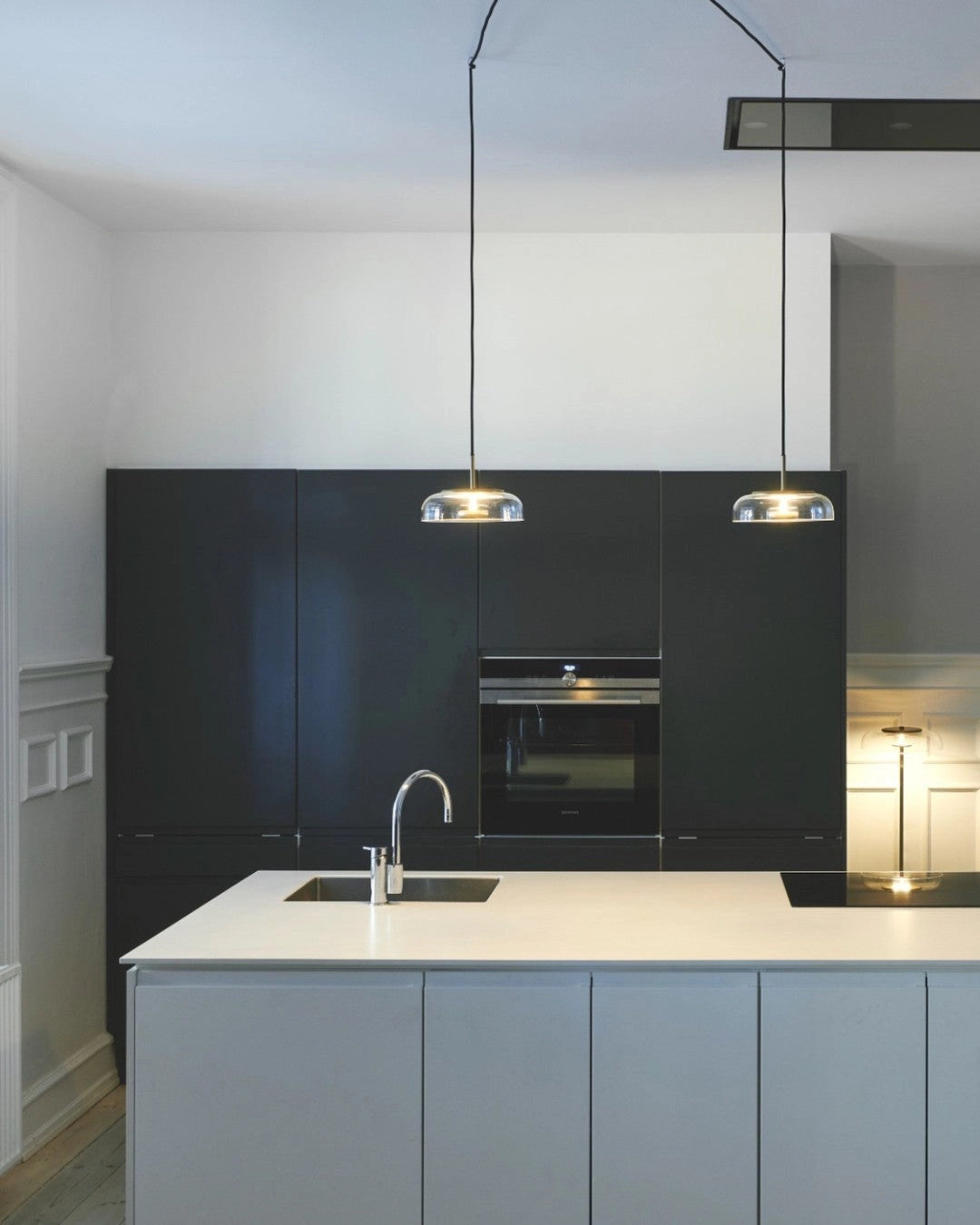 Modern kitchen with brass and chrome LED pendant lights illuminating a sleek countertop and cabinetry.