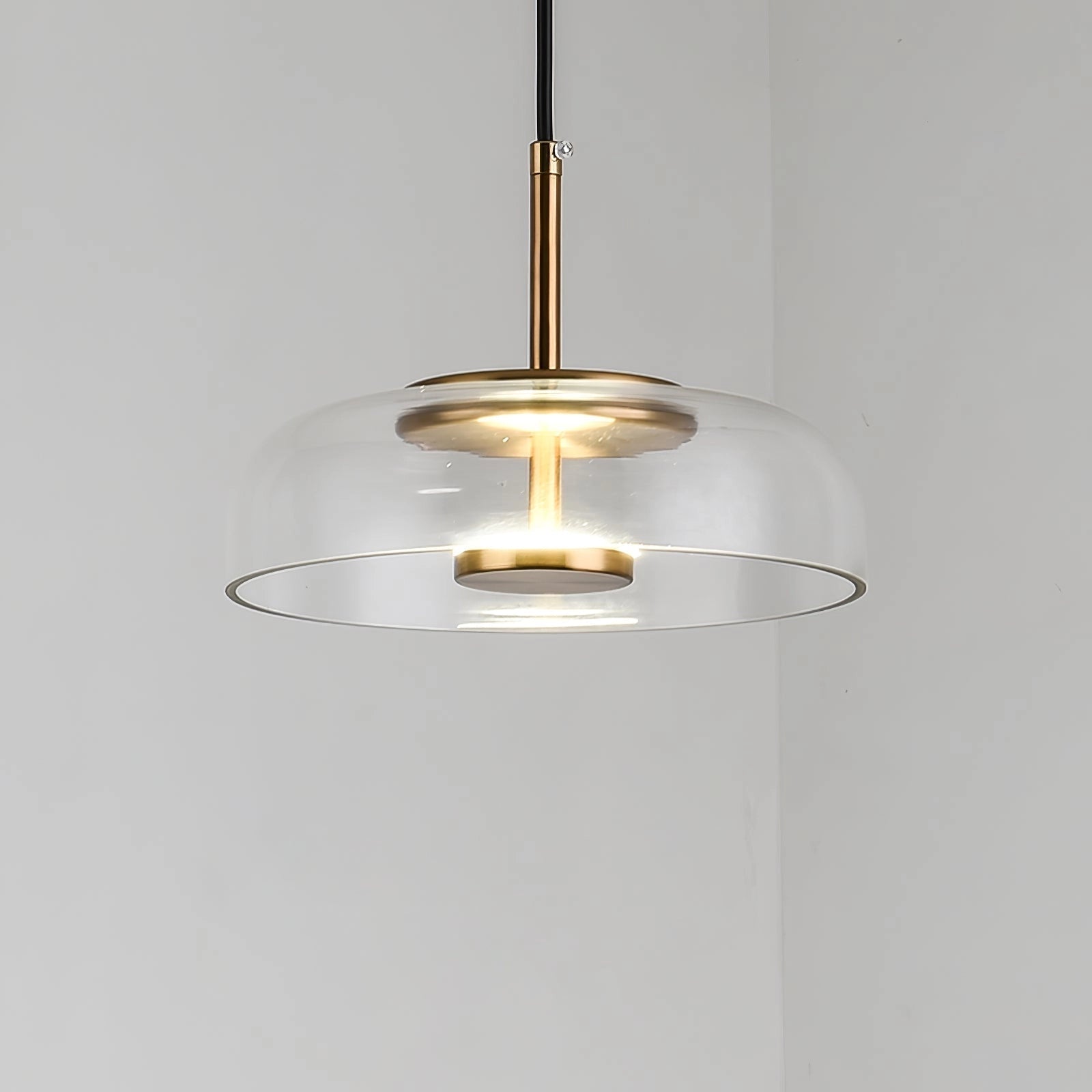 Modern brass and chrome LED pendant lights with a minimalist design, featuring sleek cylindrical metal and glass elements, suspended from the ceiling.