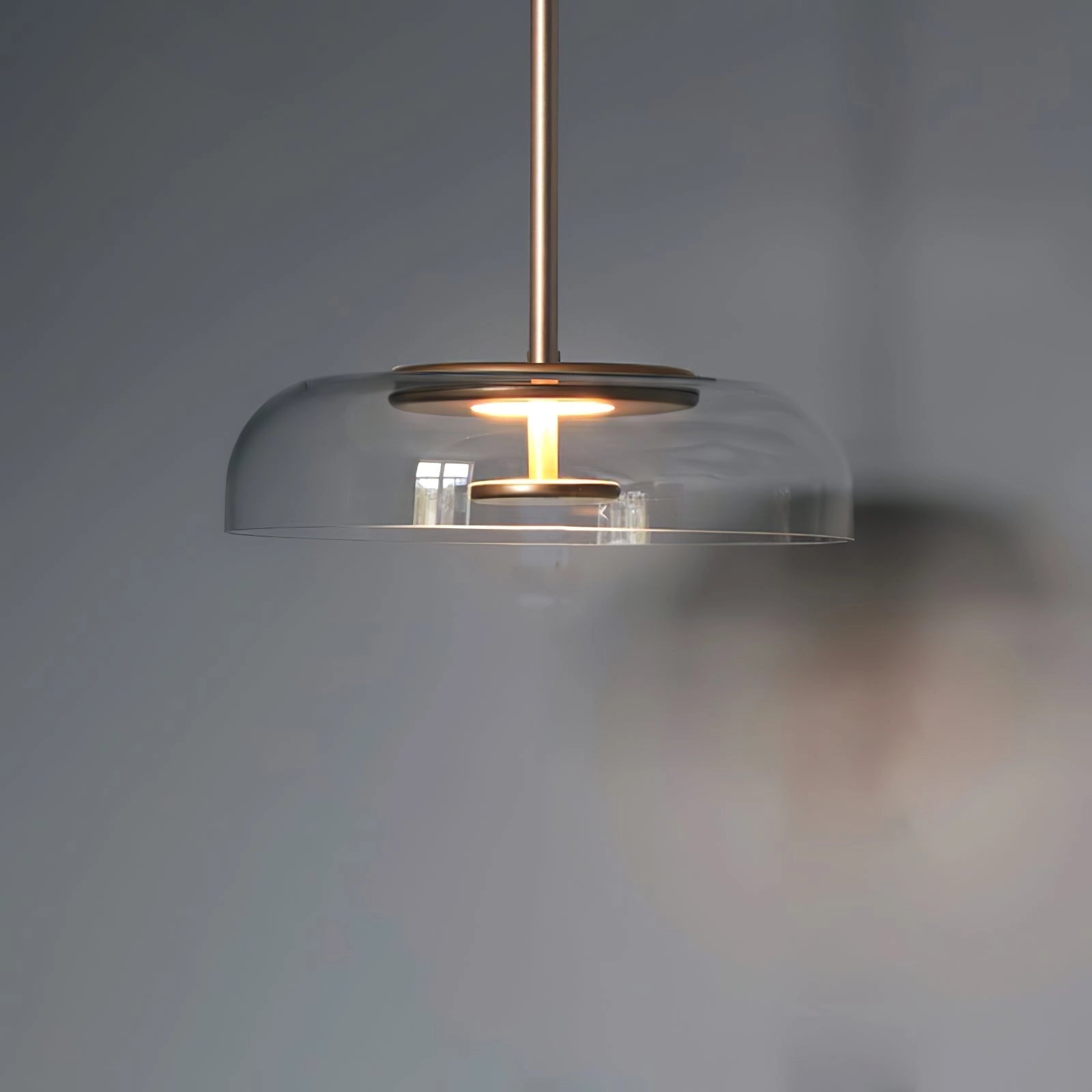 Modern brass and chrome LED pendant lights with minimalist design, featuring a circular ceiling fixture and sleek wood accents.