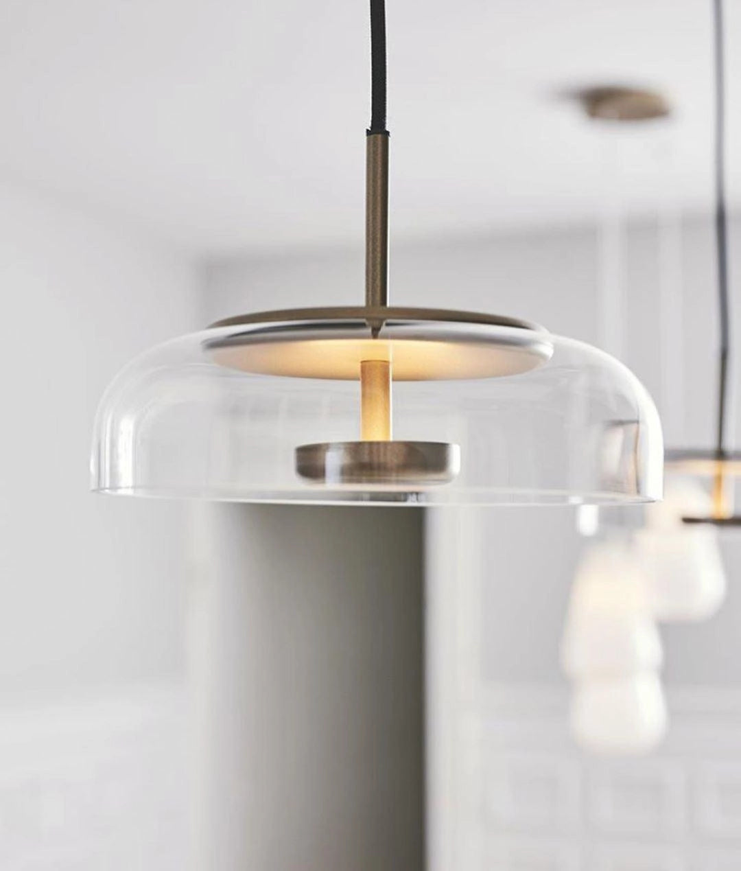 Modern brass and chrome LED pendant lights with minimalist design, featuring glass and transparent cylindrical elements.