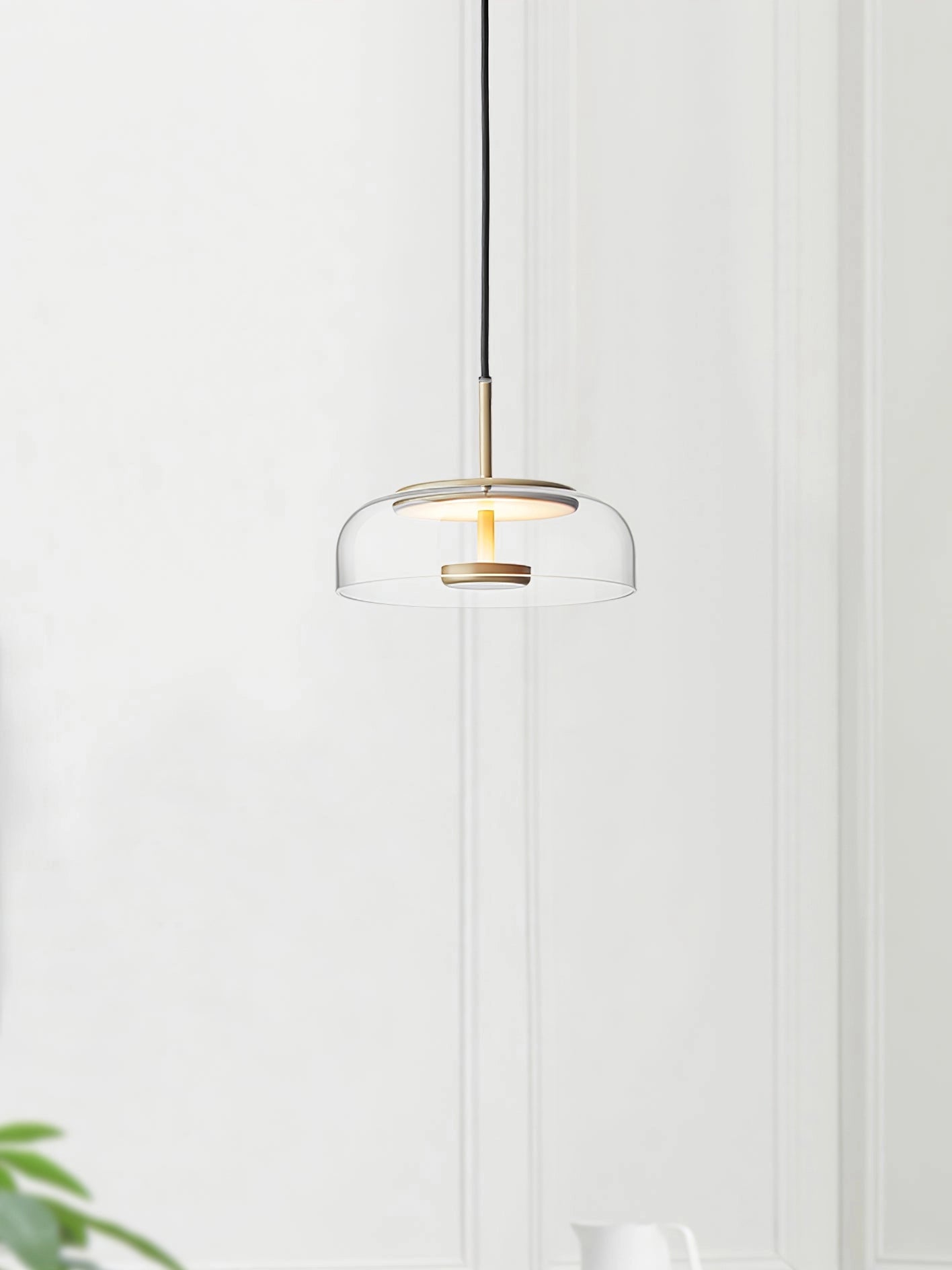 Luxury minimalist modern brass and chrome LED pendant lights hanging from the ceiling, featuring a sleek design with glass and metal elements, illuminating a stylish interior space with wooden and plant decor.