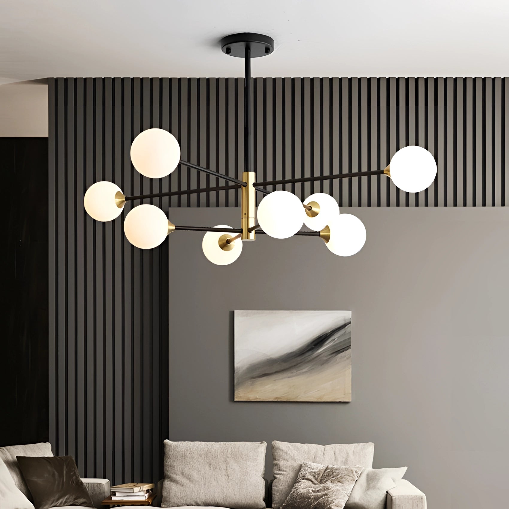 Modern brass geometric LED chandelier with mid-century minimalist design, illuminating a stylish interior space featuring white walls, wood accents, and grey textiles.