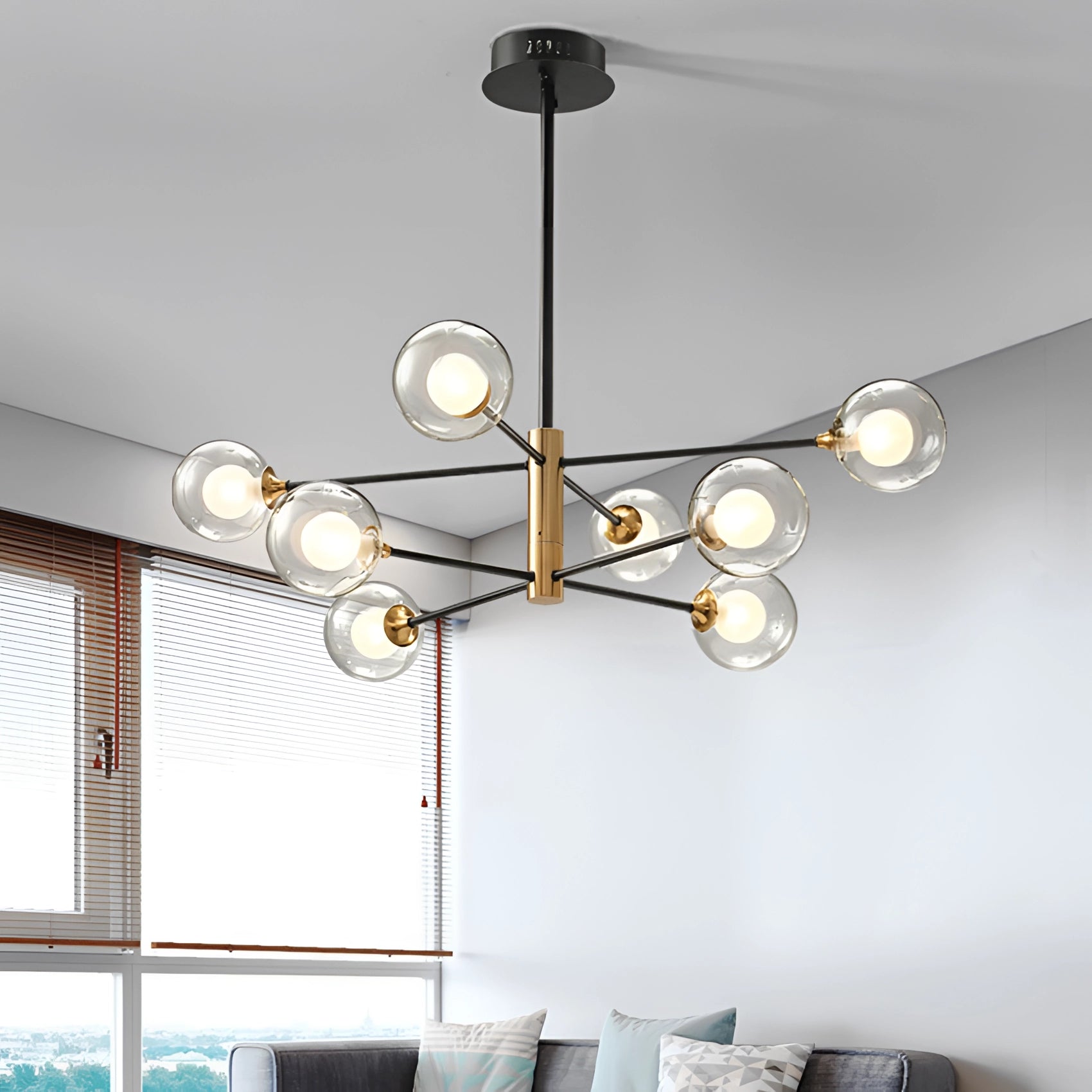 Modern brass geometric LED chandelier with mid-century minimalist design hanging in a stylish white interior featuring a couch and wall decor.