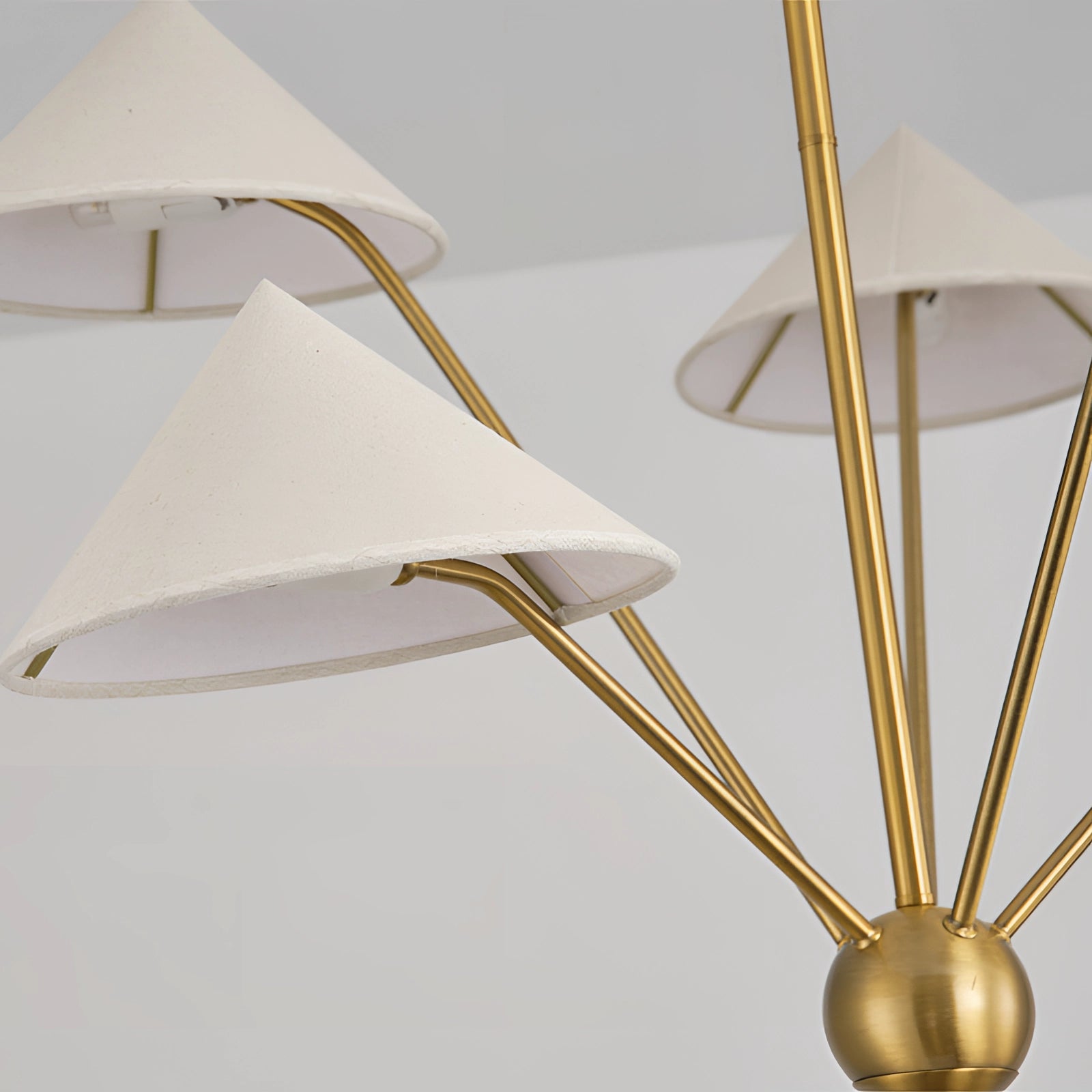 Modern brass geometric pendant chandelier with a mid-century minimalist design, featuring gold accents and an artistic arrangement of triangular shapes that cast warm tints and shades.