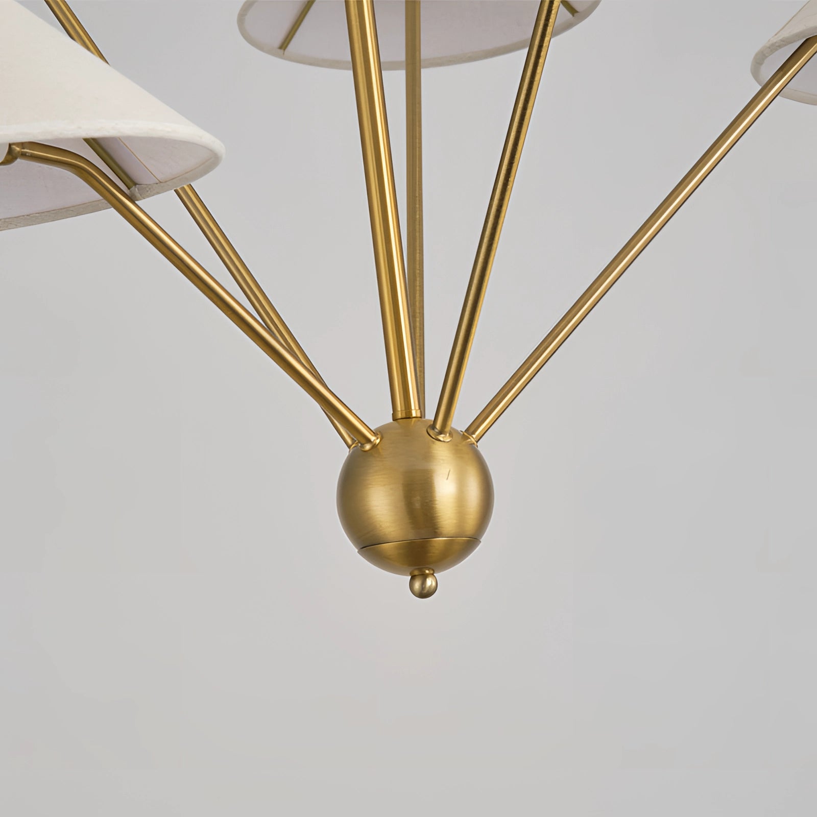 Modern brass geometric pendant chandelier with a mid-century minimalist design, featuring symmetrical metal fixtures and circular elements, hanging from a ceiling.