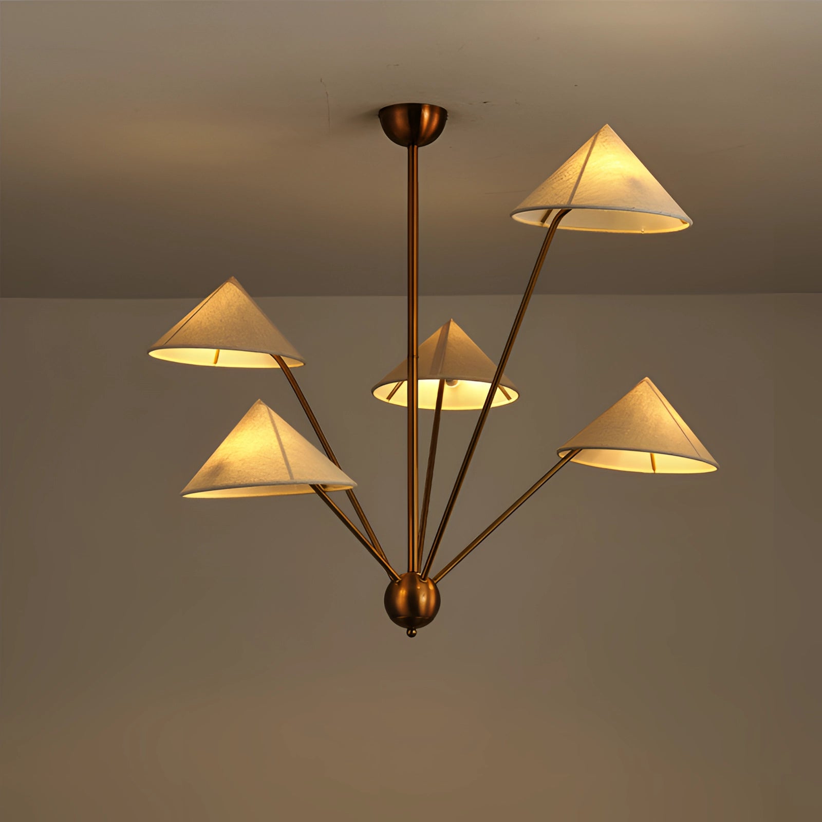 Modern brass geometric pendant chandelier with a mid-century minimalist design, featuring an amber and orange tinted triangular and rectangular pattern, hanging from a ceiling, casting a warm glow.