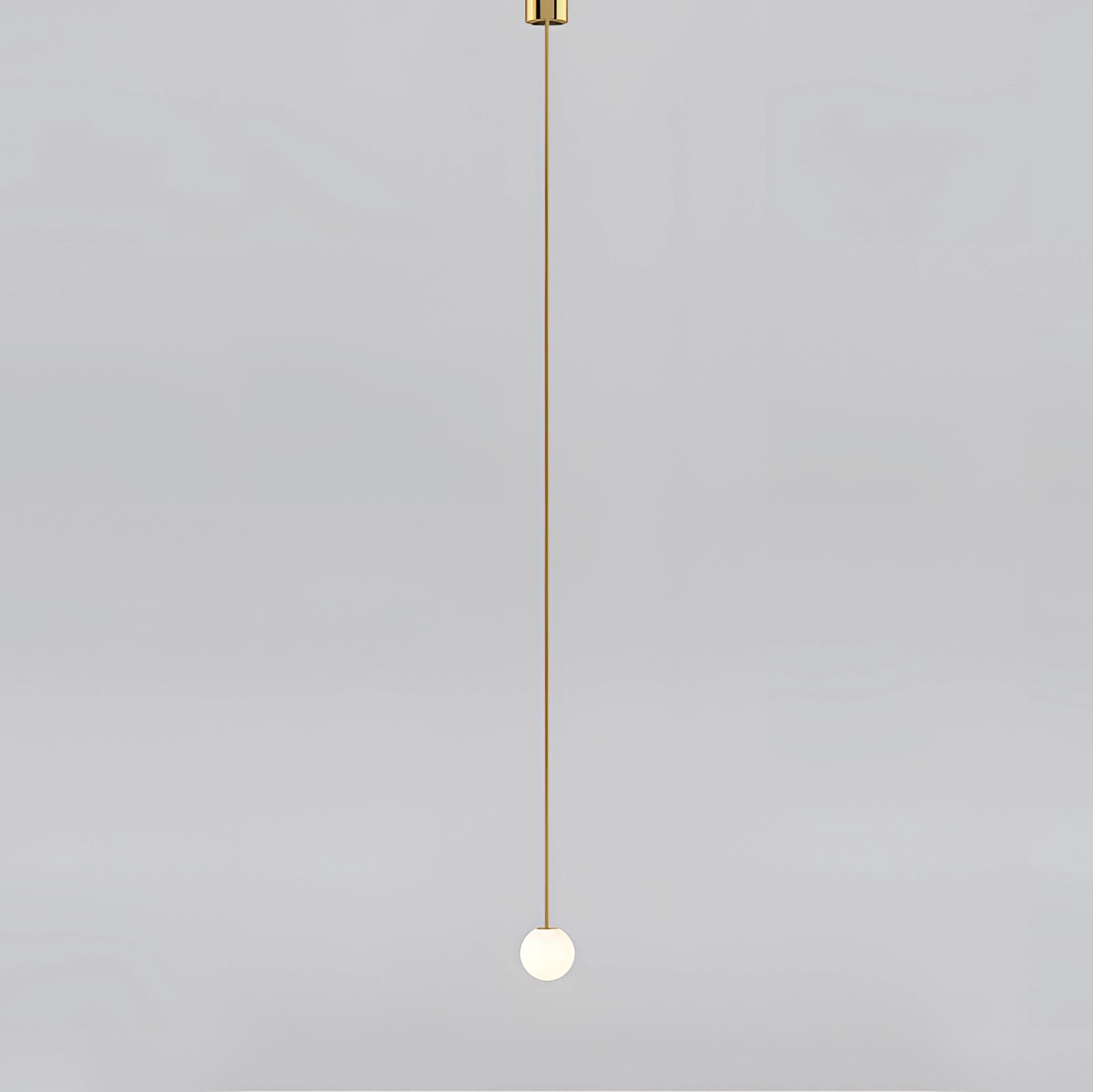 Modern brass globe pendant light with a minimalist design featuring a circular shape, hanging in a contemporary kitchen setting.