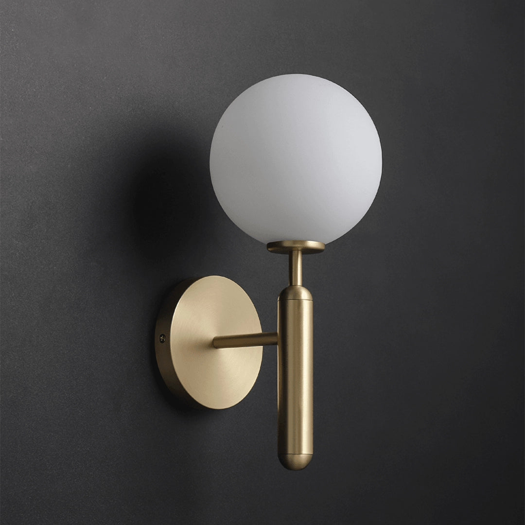 Modern brass globe wall sconce with LED light, mounted on a wooden wall, suitable for bedroom illumination.