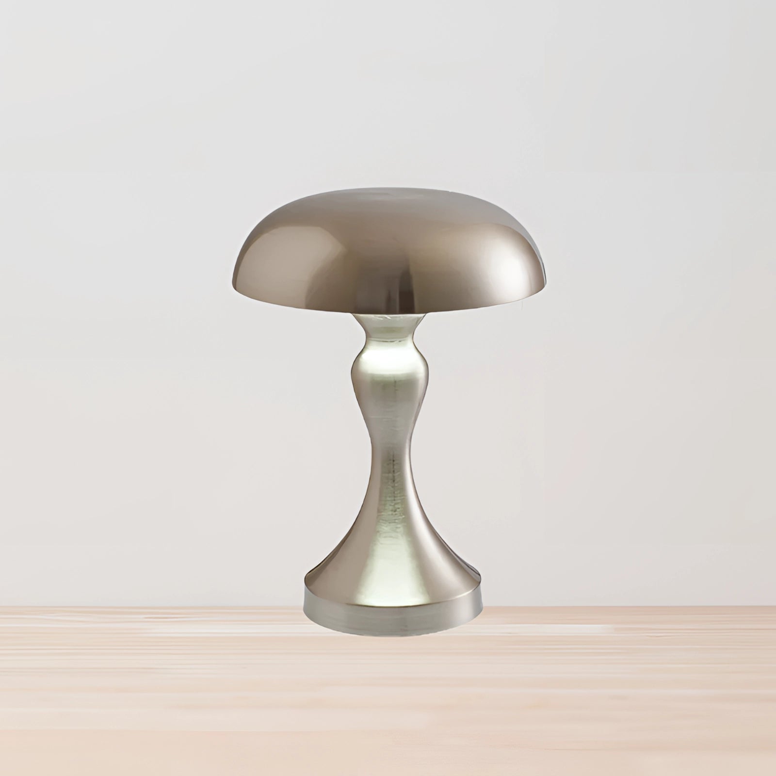 Modern silver brass mushroom table lamp with a sleek metal finish, featuring an elegantly curved design and circular elements, set against a wooden surface backdrop.