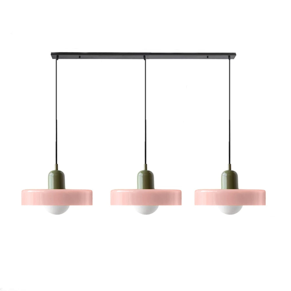 Modern brass pendant lights with red cable hanging above a wooden table and shelving in an industrial-style kitchen.