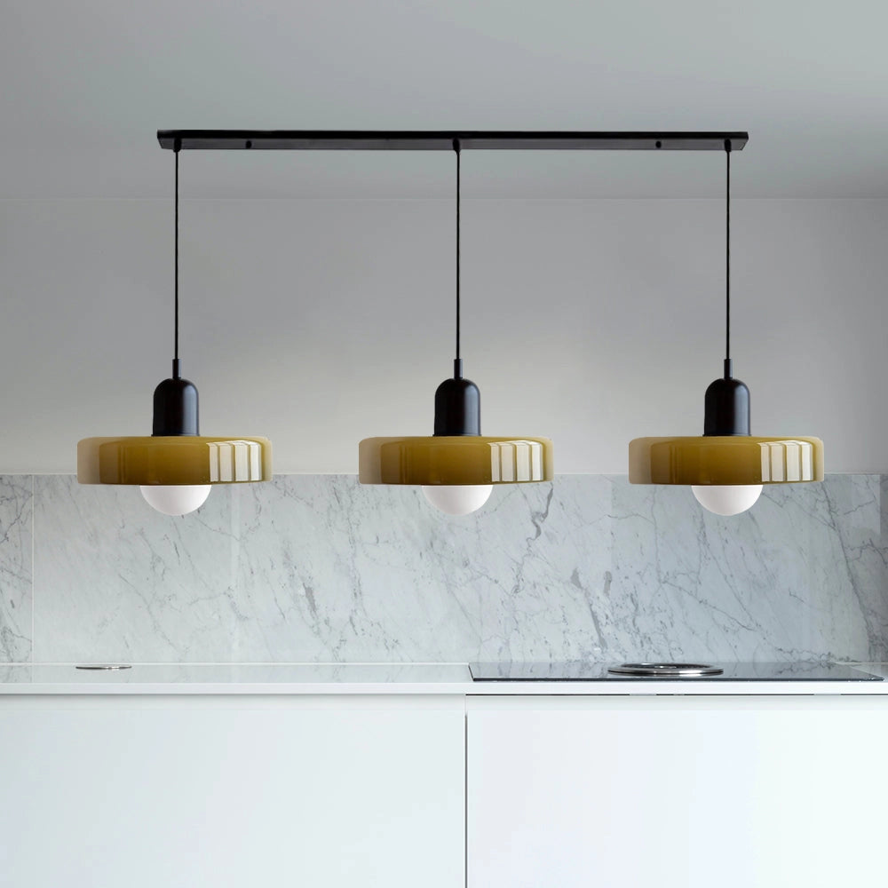 Modern brass pendant light with red cable hanging above a wooden kitchen island with grey shelving and beige flooring.