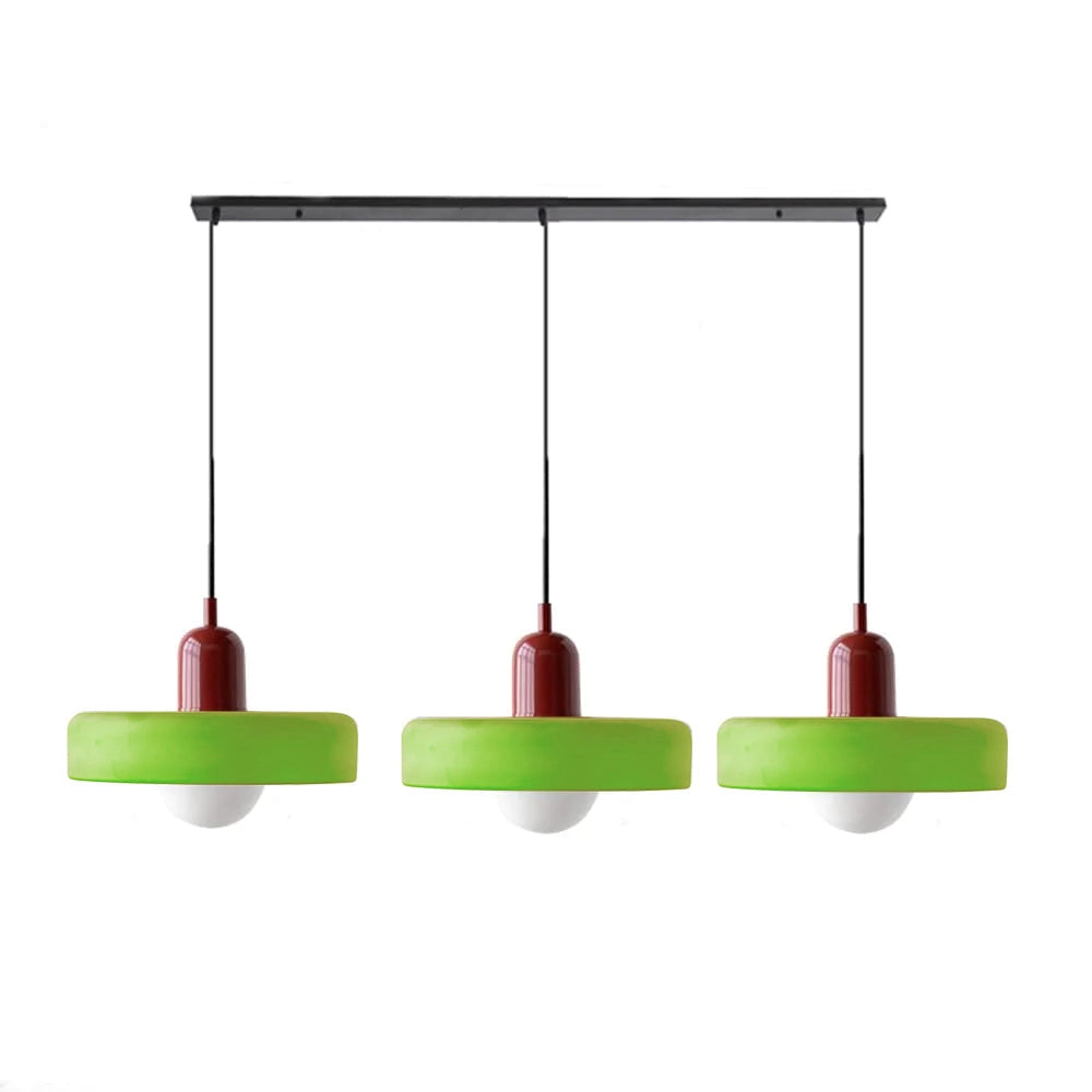 Modern brass pendant light with red cable, adjustable, hanging from ceiling in an industrial kitchen setting.