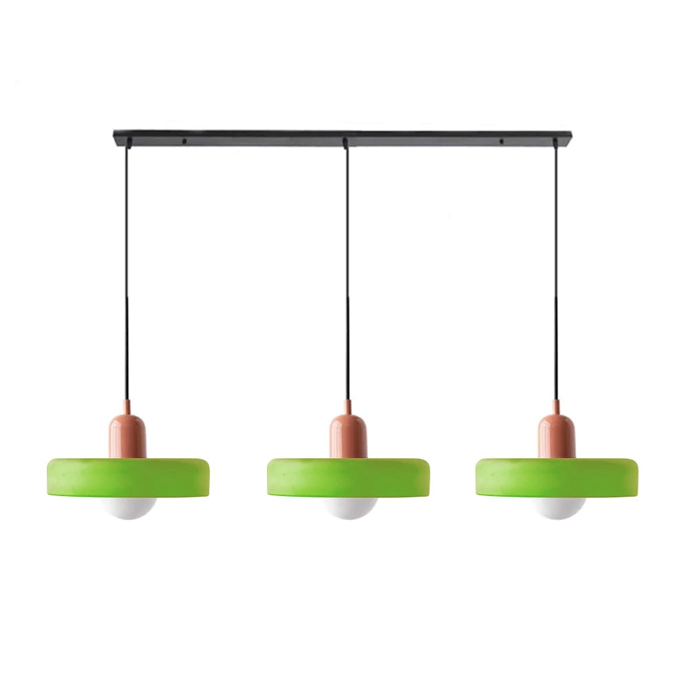 Modern brass pendant lights with red cable, adjustable, hanging from a wooden ceiling, above a kitchen shelf, featuring industrial design elements.