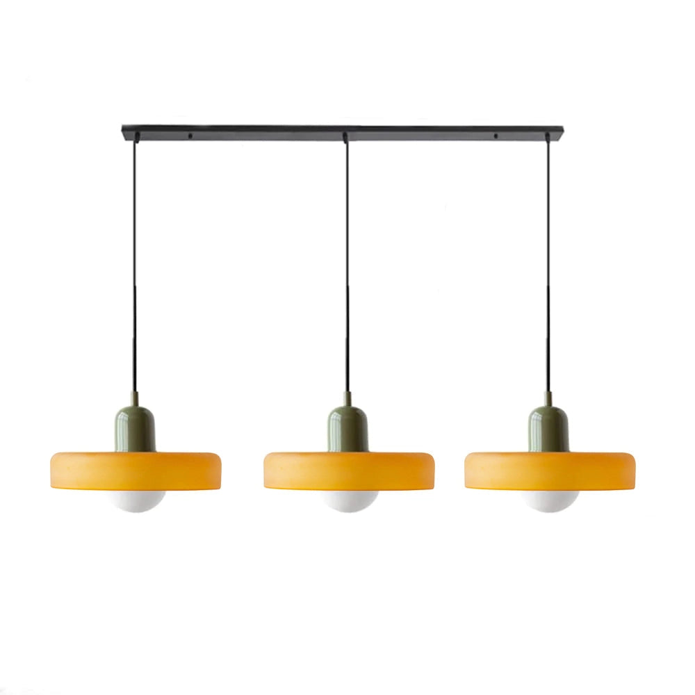 Modern brass pendant lights with red cable, adjustable, hanging from ceiling in an industrial kitchen setting.