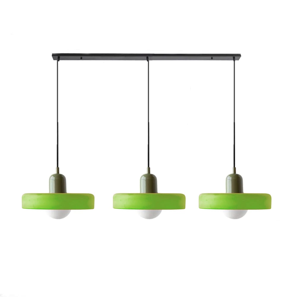 Modern brass pendant lights with red cable hanging from the ceiling, adjustable height, illuminating an industrial kitchen with a rectangular table and shelving units.