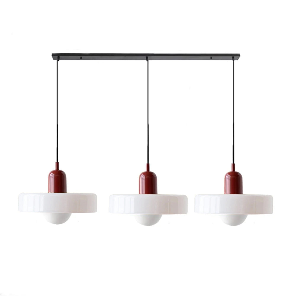 Modern brass pendant light with red cable, hanging from the ceiling in an industrial kitchen setting.