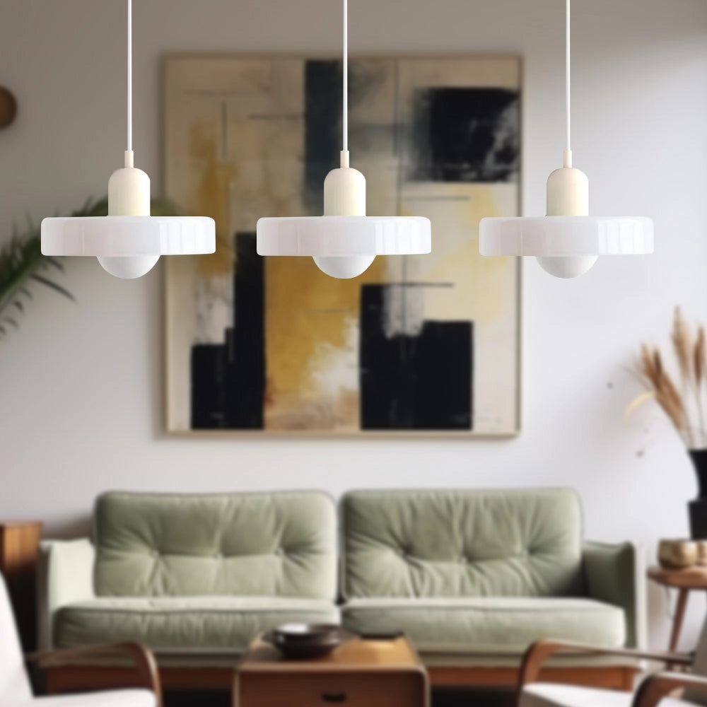 Modern brass pendant lights with a red cable, adjustable, featuring three white lampshades, installed in an industrial kitchen setting.
