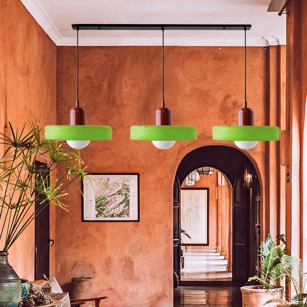 Modern brass pendant lights with red cable hanging in an industrial kitchen, featuring houseplants and wooden interior design elements.