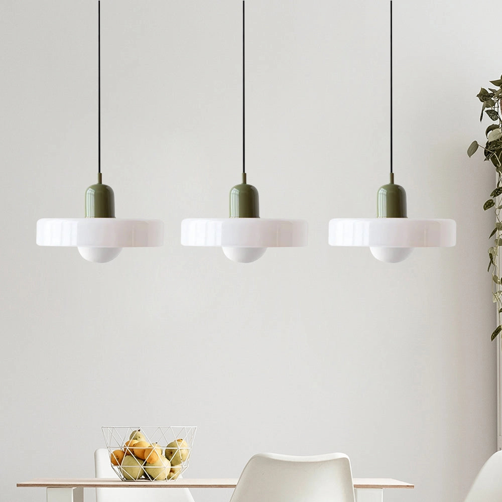 Modern brass pendant lights with white and green shades, featuring three adjustable heads, red cable, and wooden accents, illuminating an industrial kitchen interior.