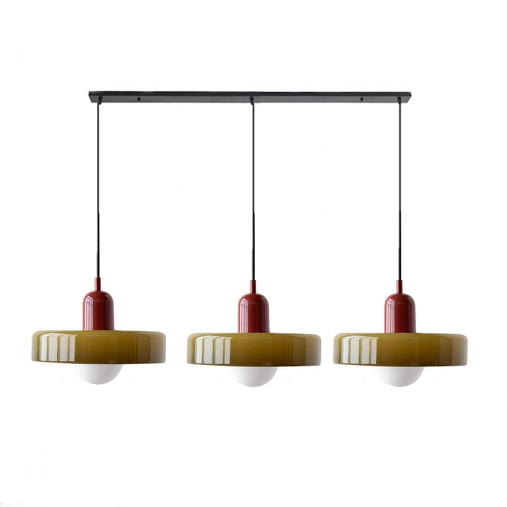 Modern brass pendant lights with adjustable red cable hanging from a ceiling in an industrial kitchen setting.