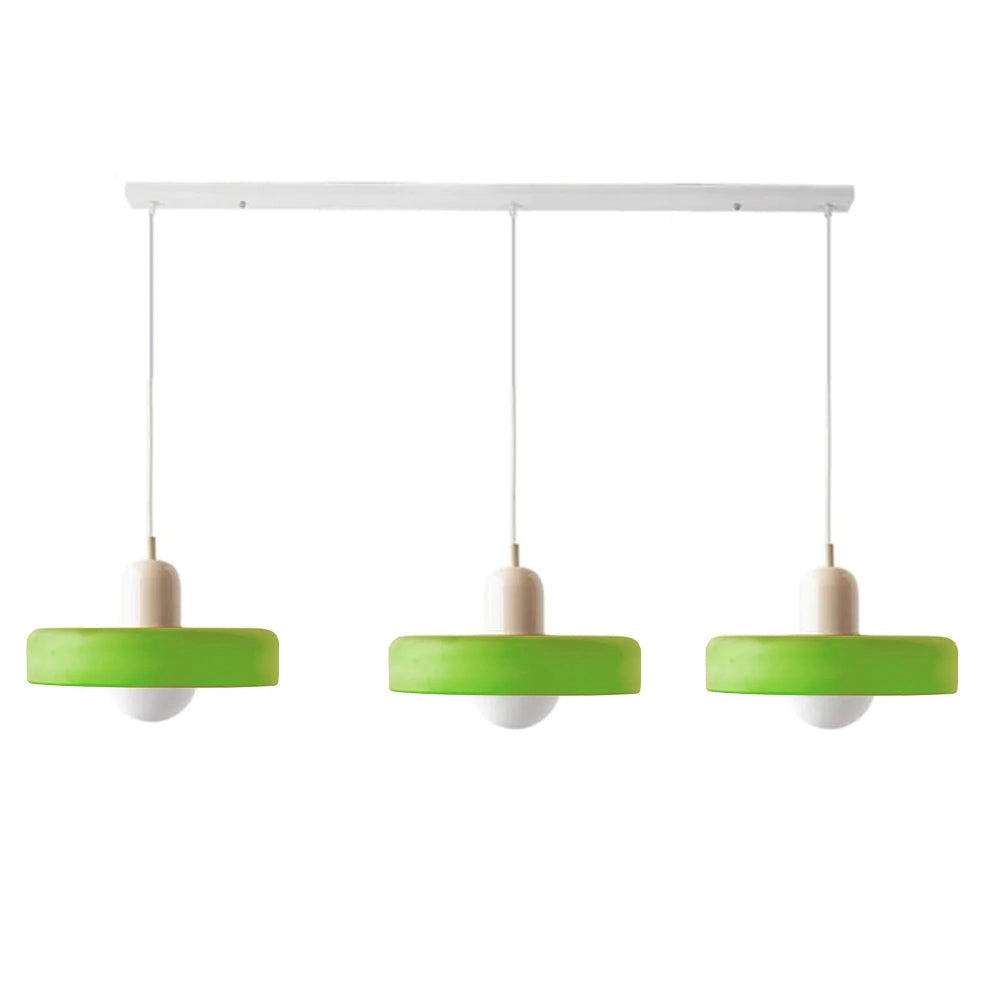 Modern brass pendant lights with a red cable, hanging from an industrial kitchen ceiling. The lights have a sleek, adjustable design with a metallic finish.