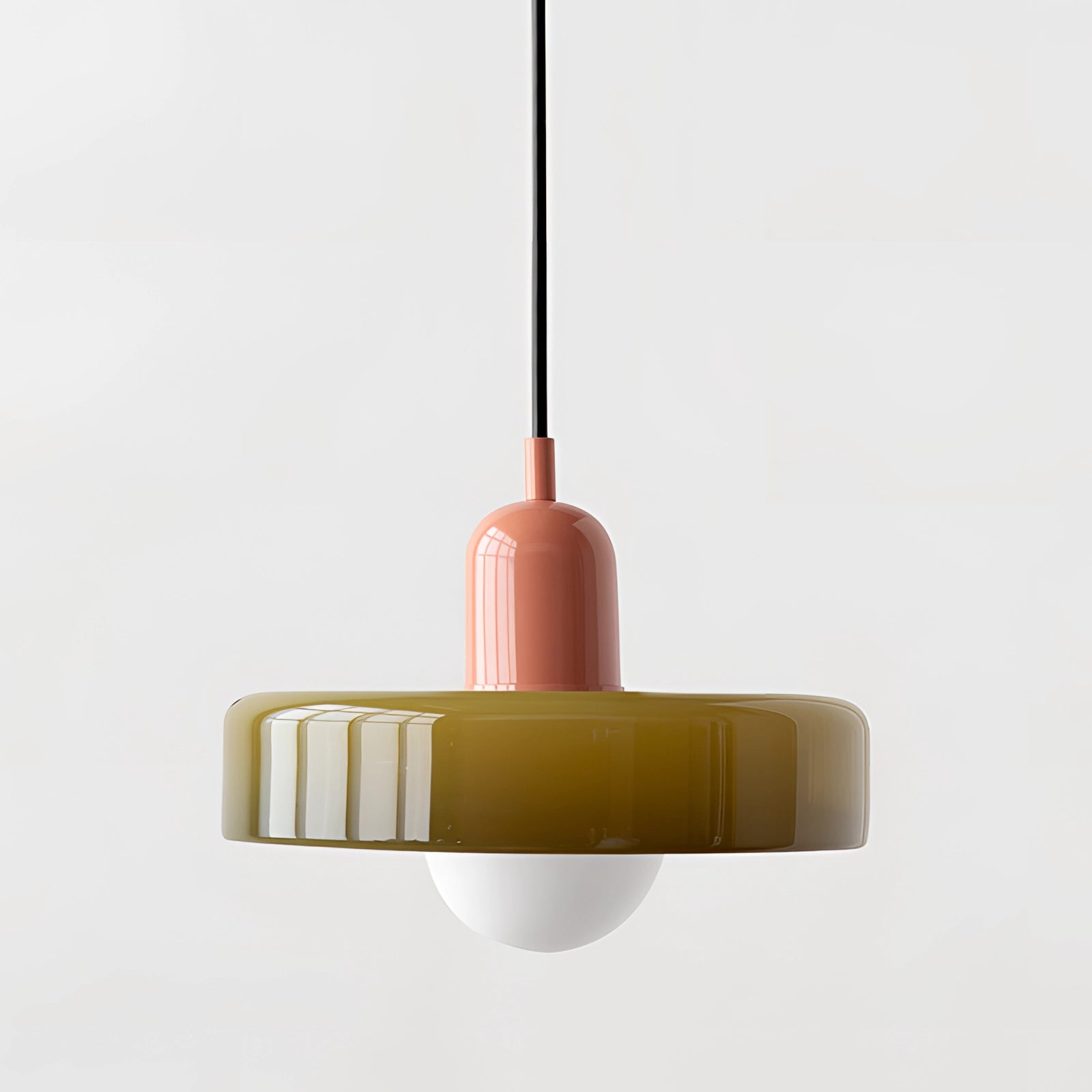 Modern brass pendant light with adjustable red cable hanging over wooden table in industrial kitchen.