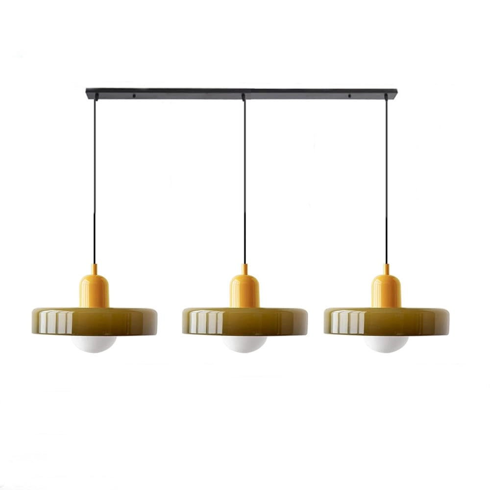 Modern brass pendant lights with red cable hanging above wooden shelving unit in an industrial kitchen.