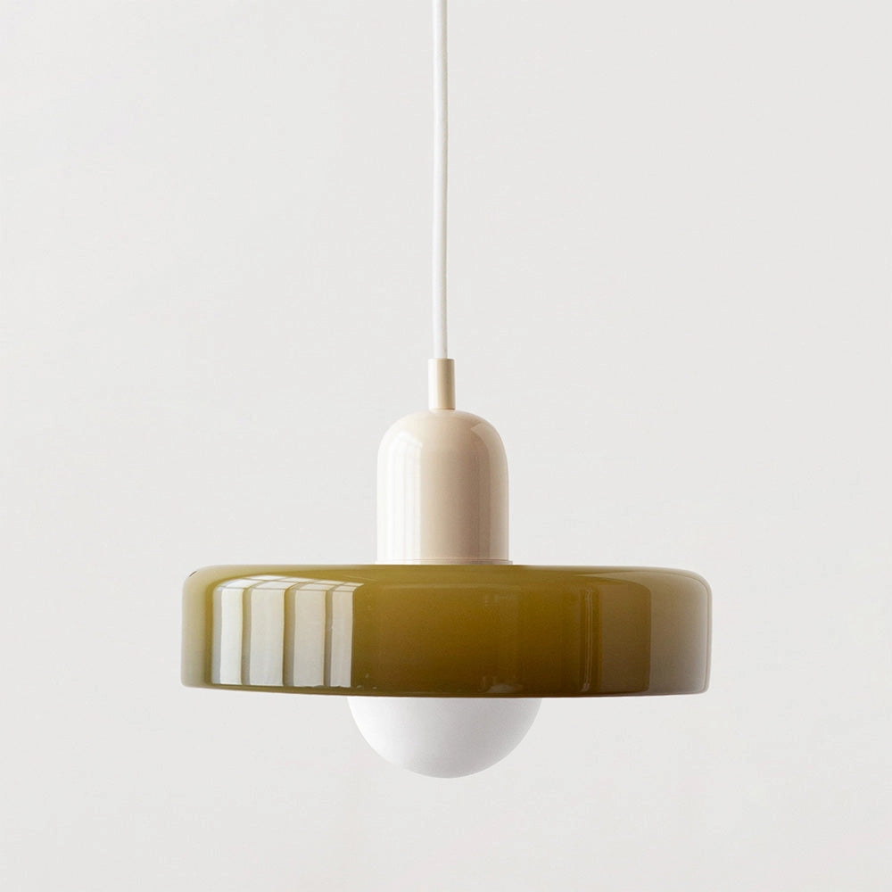 Modern brass pendant light with a red cable hanging from a wooden ceiling in an industrial kitchen setting.