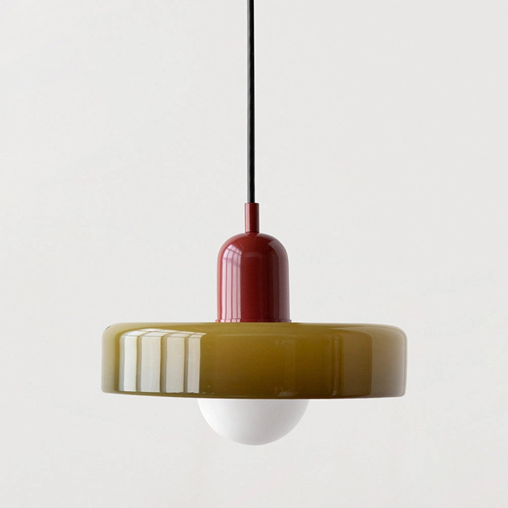 Modern brass pendant light with adjustable height, featuring a red cable, hanging in an industrial kitchen setting.