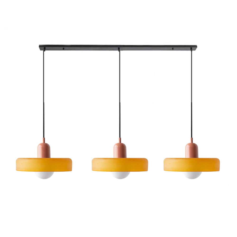 Modern brass pendant lights with red cable, hanging above a wooden rectangular table in an industrial kitchen.