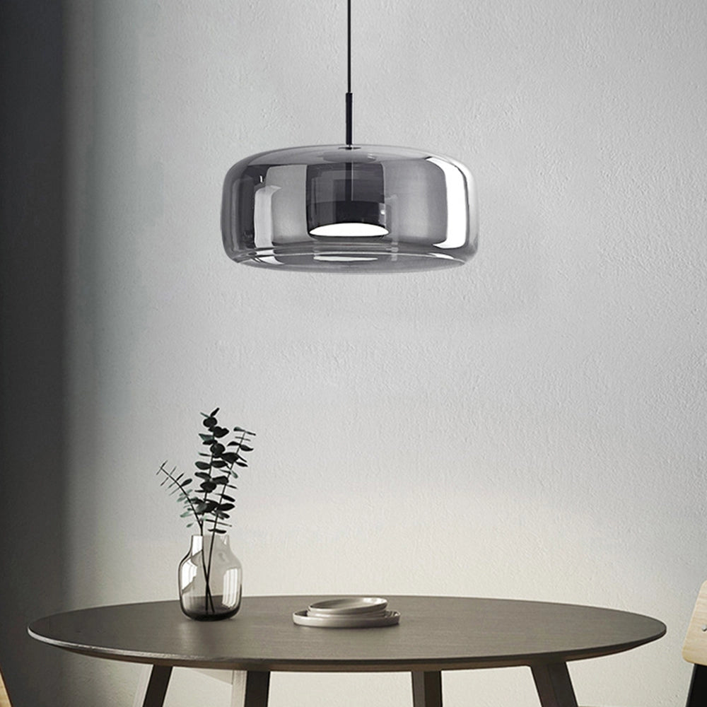 A modern brushed brass glass pendant light hanging over a dining table, featuring a sleek and contemporary design suitable for kitchens and dining areas.
