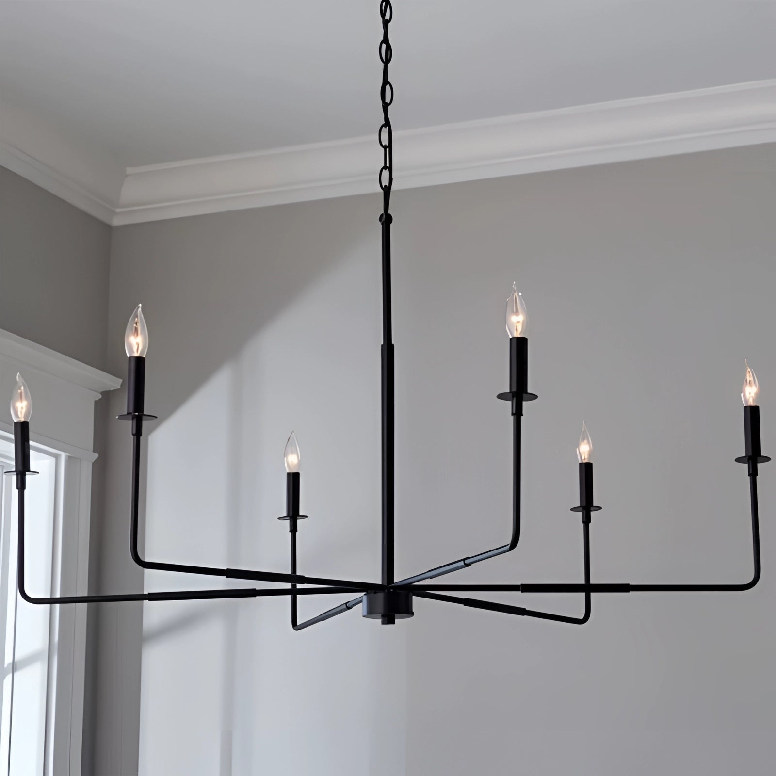 Modern chrome linear chandelier with a sleek black finish, featuring minimalist design elements and multiple candle-style lights, suspended from the ceiling.