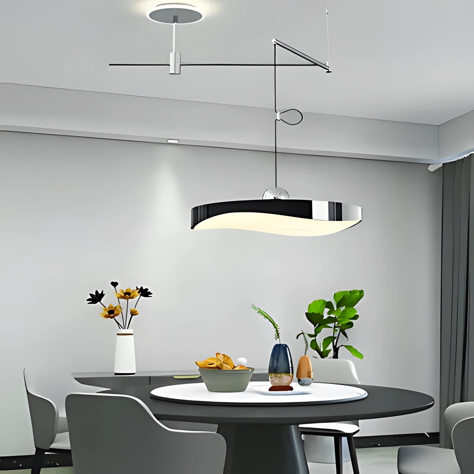 Modern circular LED pendant light in black, sized 50cm, hanging above a table in a contemporary kitchen setting with minimalist interior design. A green plant is visible nearby, accentuating the clean and sleek lines of the space.