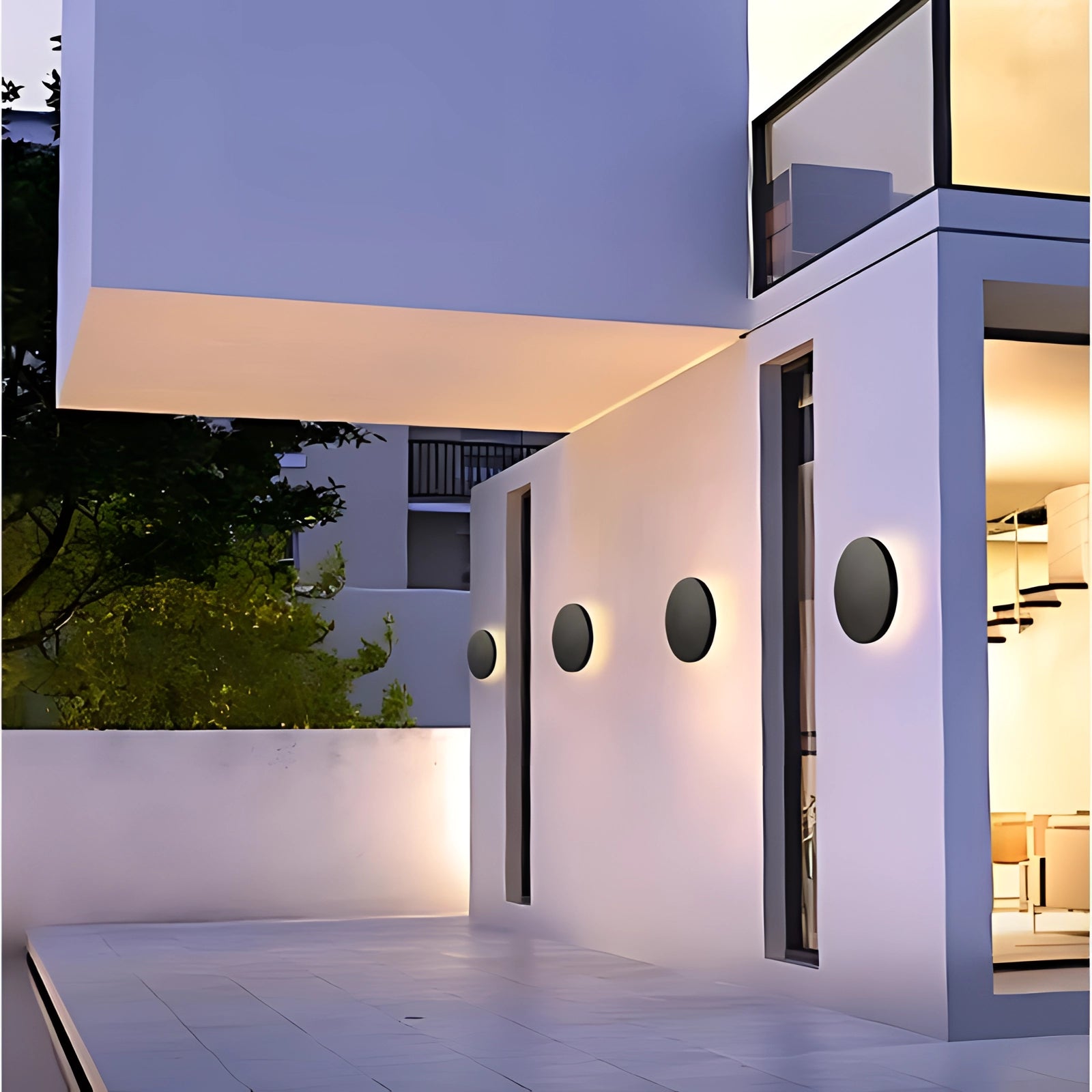 Modern circular LED wall lights with a warm white glow installed along contemporary outdoor stairs, enhancing the architectural design of the building facade with their sleek and stylish appearance.