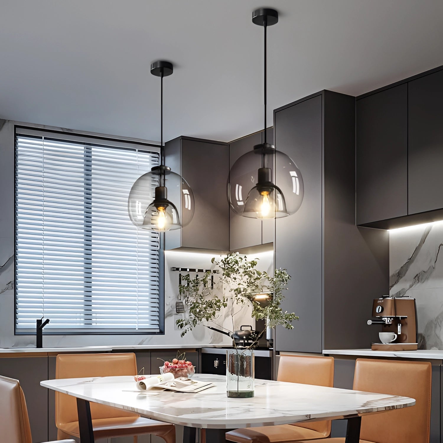Modern clear glass pendant lights in a stylish globe design hanging above a wooden table with grey chairs, indoor plant, and contemporary interior design elements.