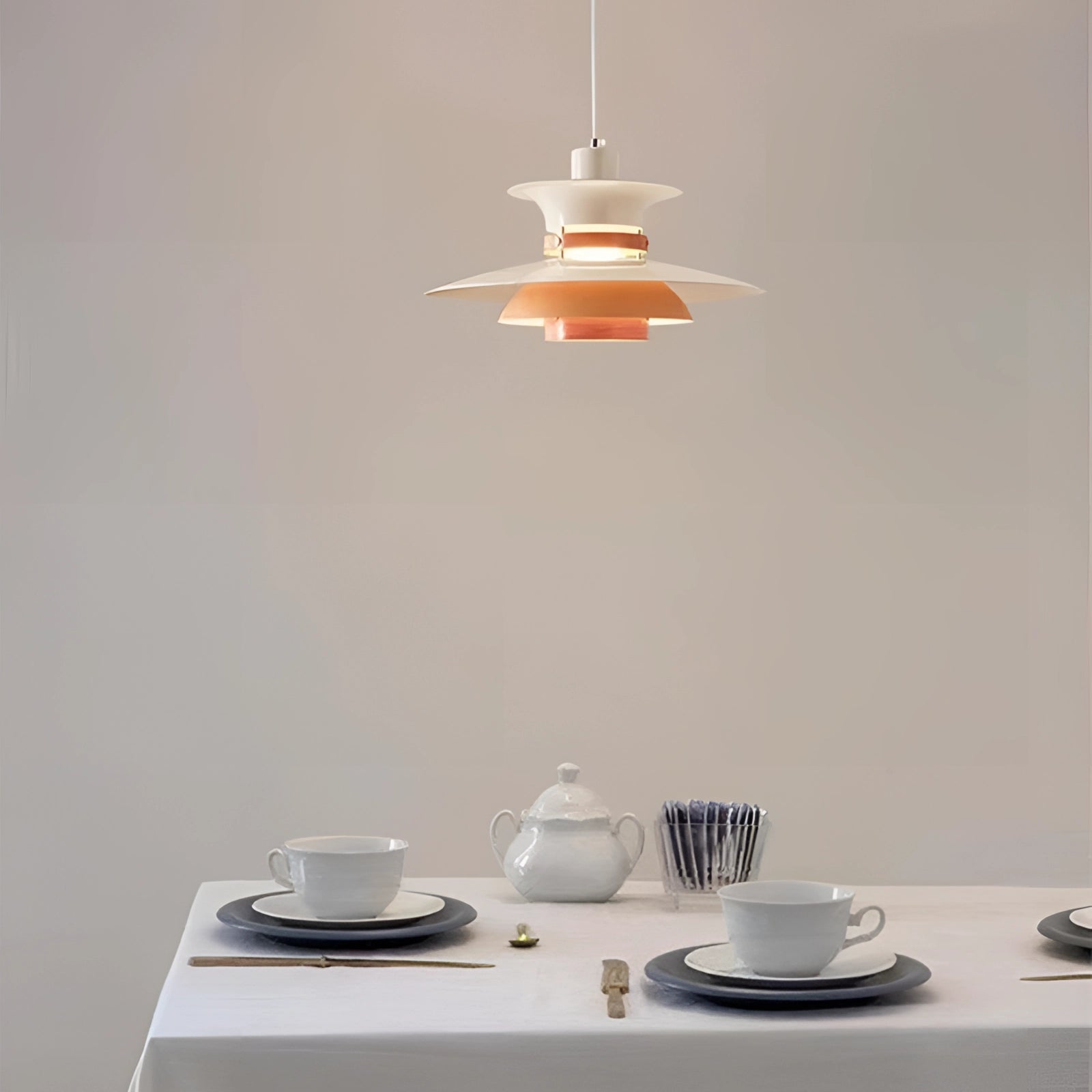 Modern colorful pendant lighting fixture with a Scandinavian design, featuring a multi-tiered structure hanging above a set table with dishware and serveware.