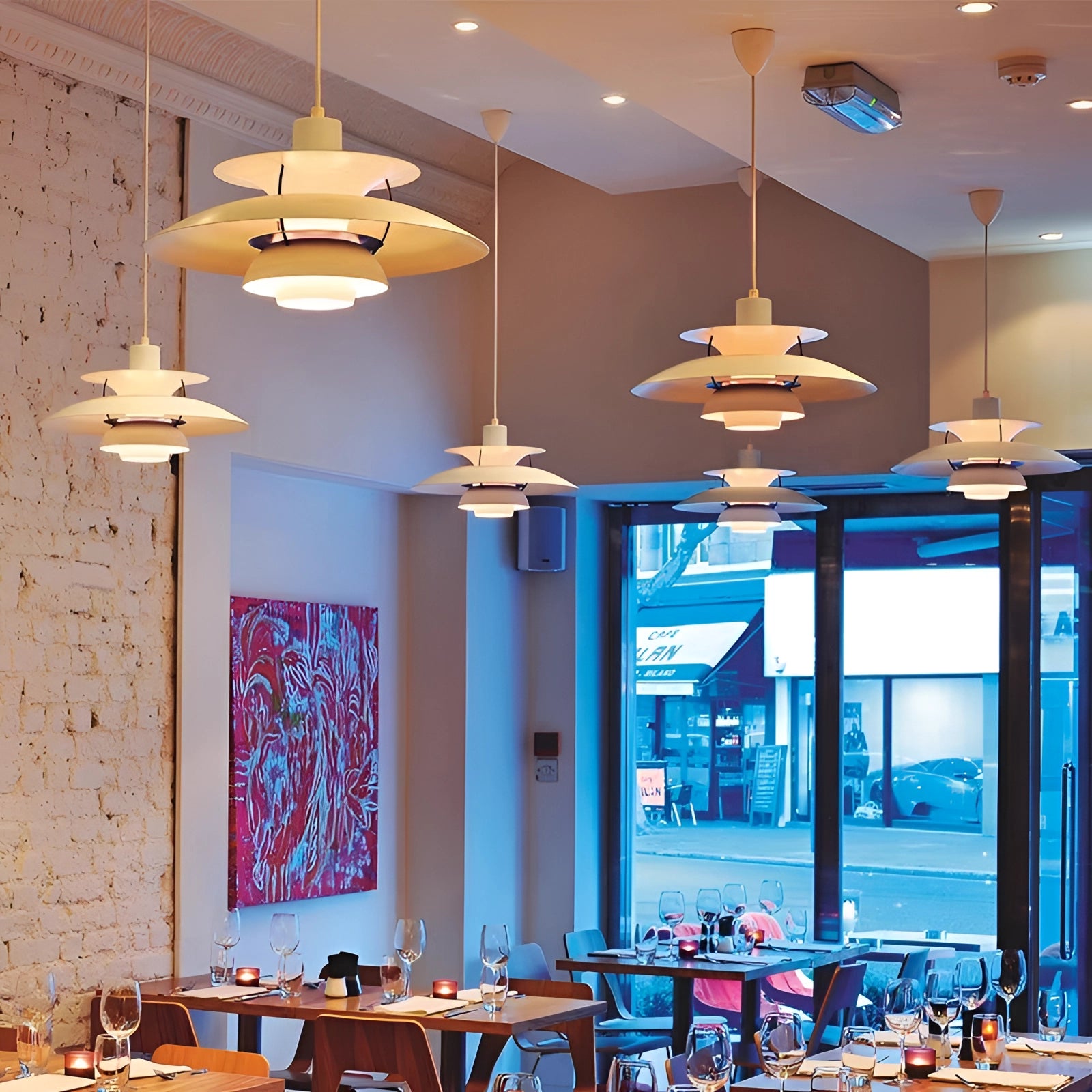 Modern Scandinavian design multi-tiered colorful pendant lighting hanging in a stylish interior space with a table and chairs, showcasing a harmonious blend of azure and neutral tones.