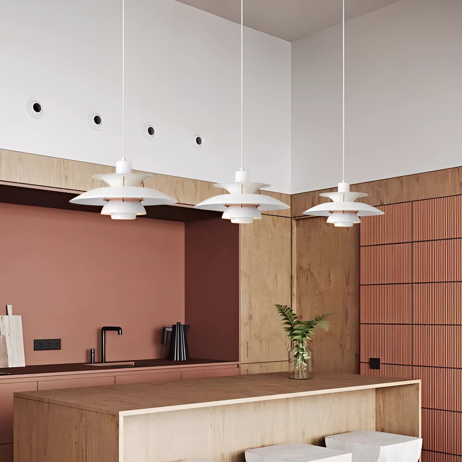 Modern colorful pendant lighting with a Scandinavian design, featuring a multi-tiered arrangement, hanging in a stylish interior setting with wooden flooring and houseplants.