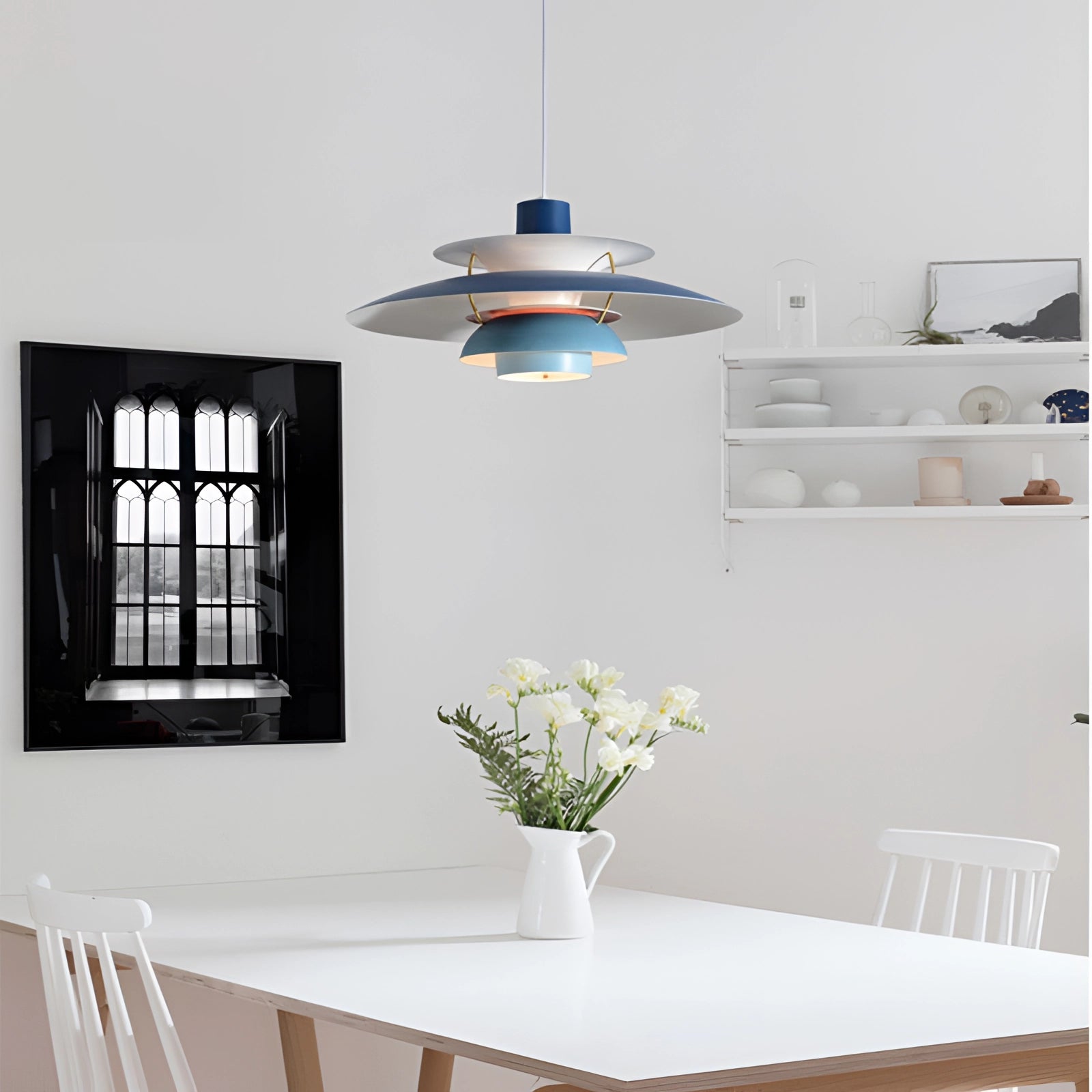 Modern colorful pendant lighting with a Scandinavian design, featuring a multi-tiered style, hanging above a table in a contemporary interior setting with a mix of furniture, plants, and decorative elements like a white vase and shelving near a window.